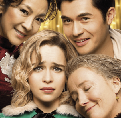 Four people, three women and one man, close together with a gold curtain in the background. The woman at the front has blonde hair and a worried expression, the woman on the right has gray hair and is smiling with eyes closed, and the other two are smiling and looking at the camera.