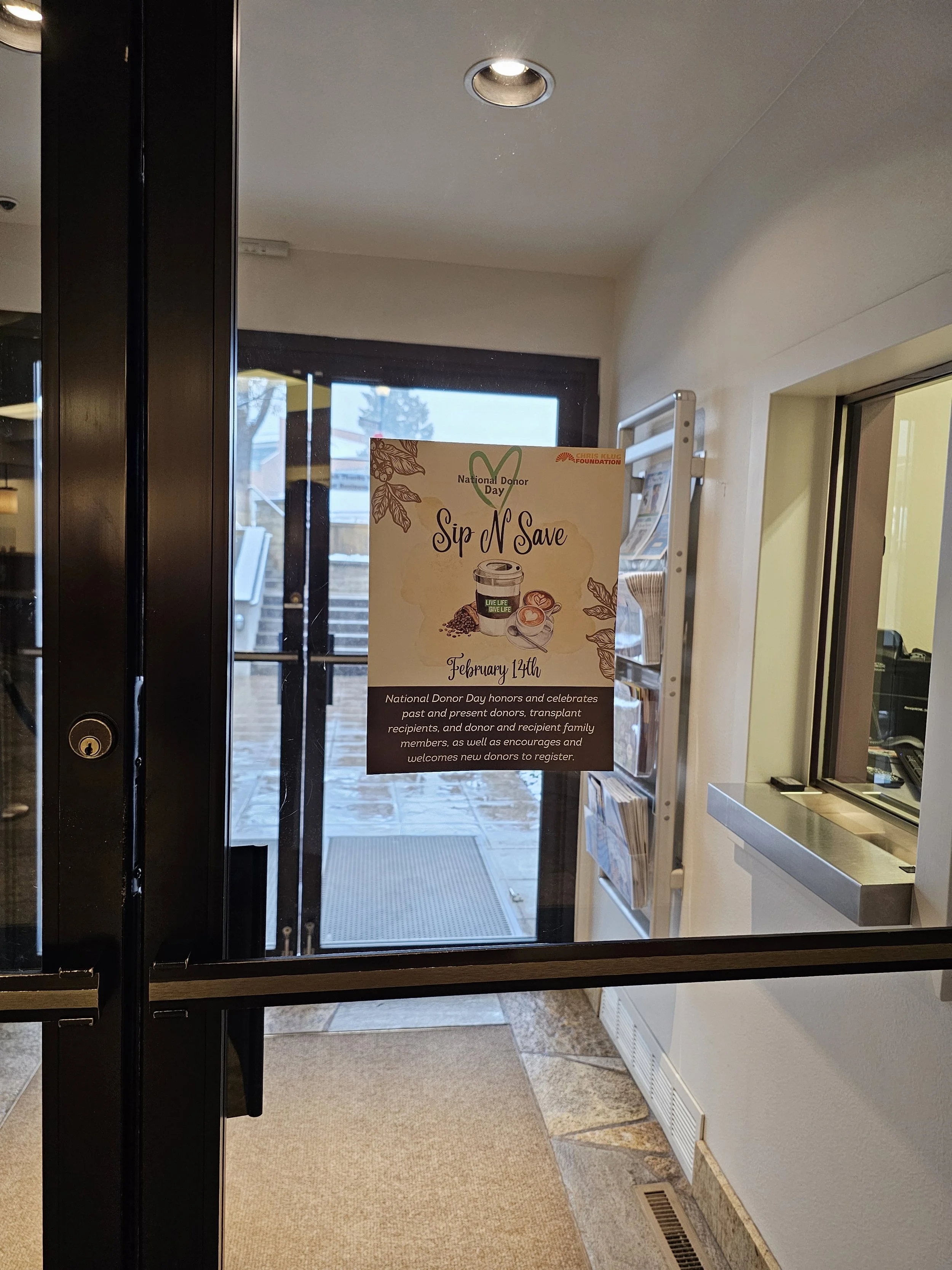 Poster on glass door promoting National Donor Day event on February 14th, with information about honoring donors and encouraging new donors to register.