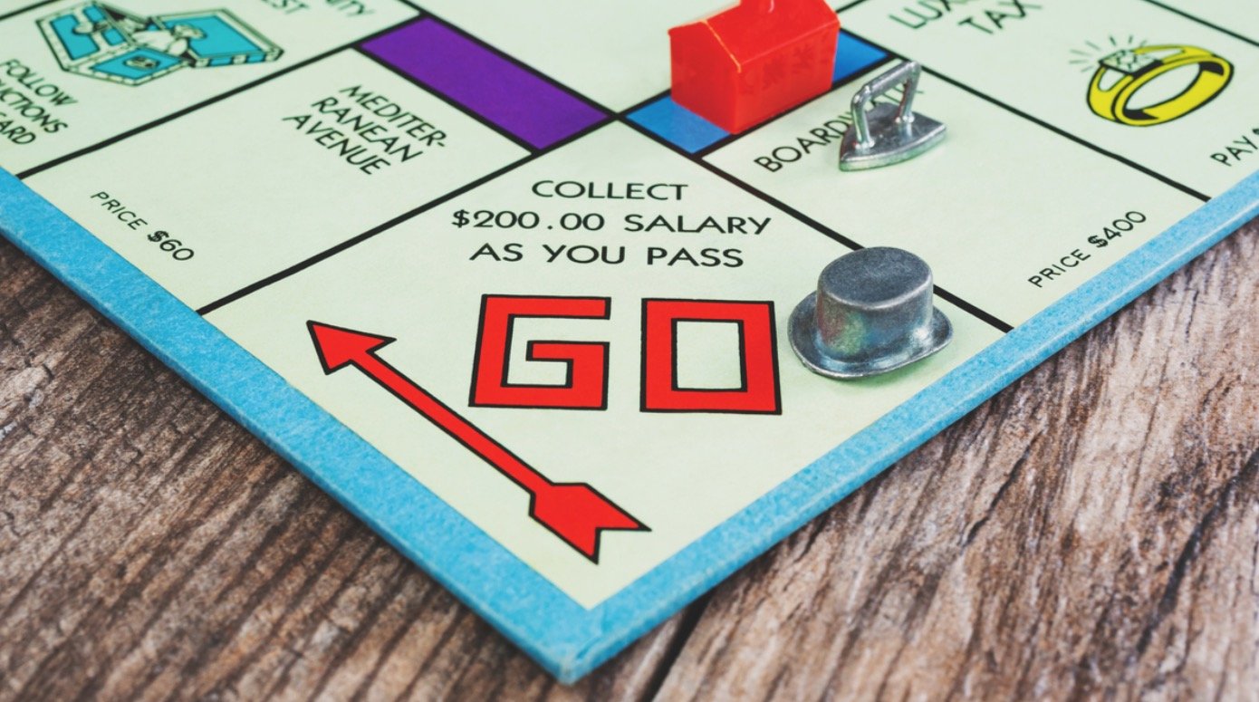 Monopoly game board with hat token on the "Go" square.
