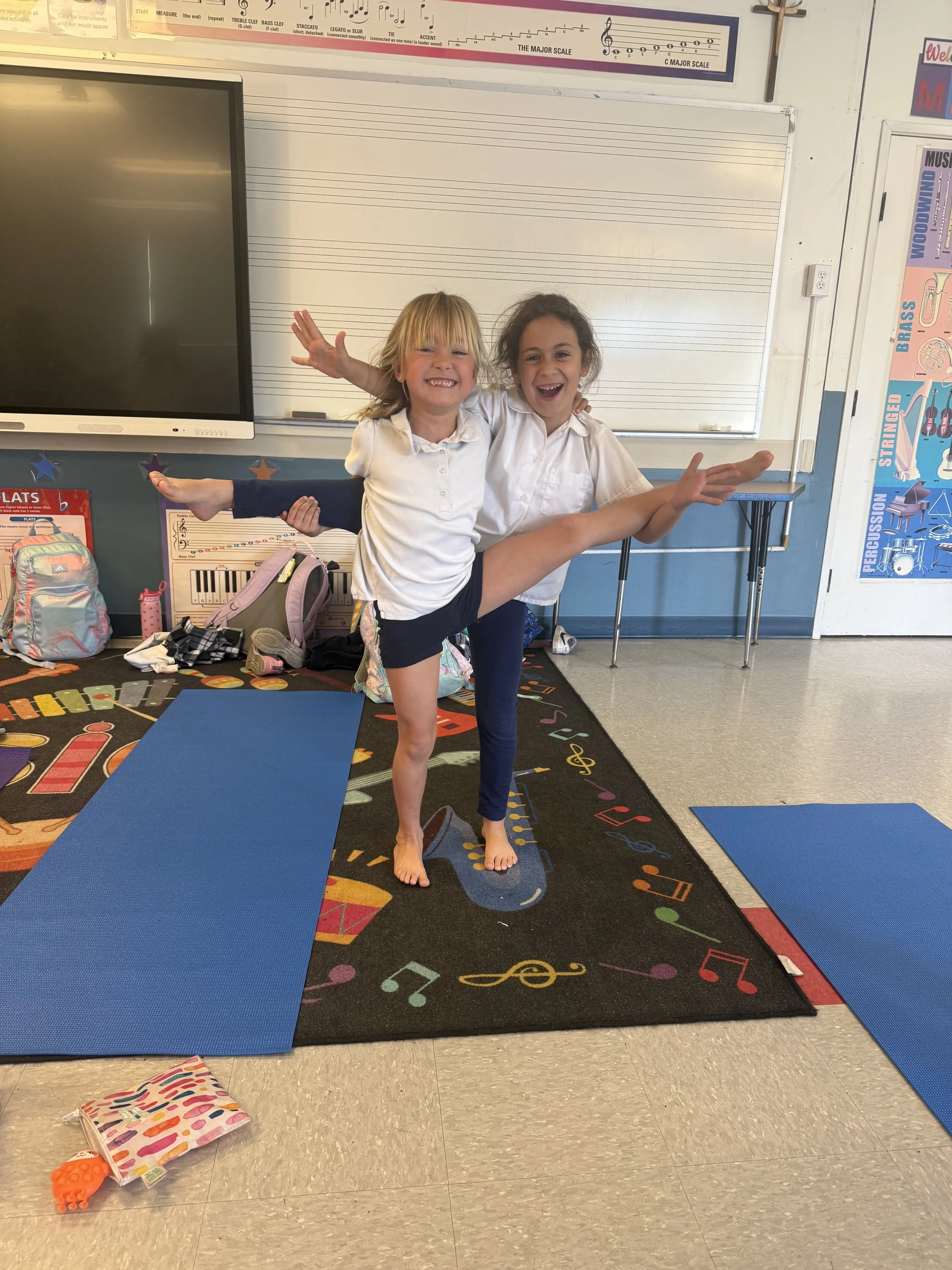 2 young children smiling doing partner yoga poses