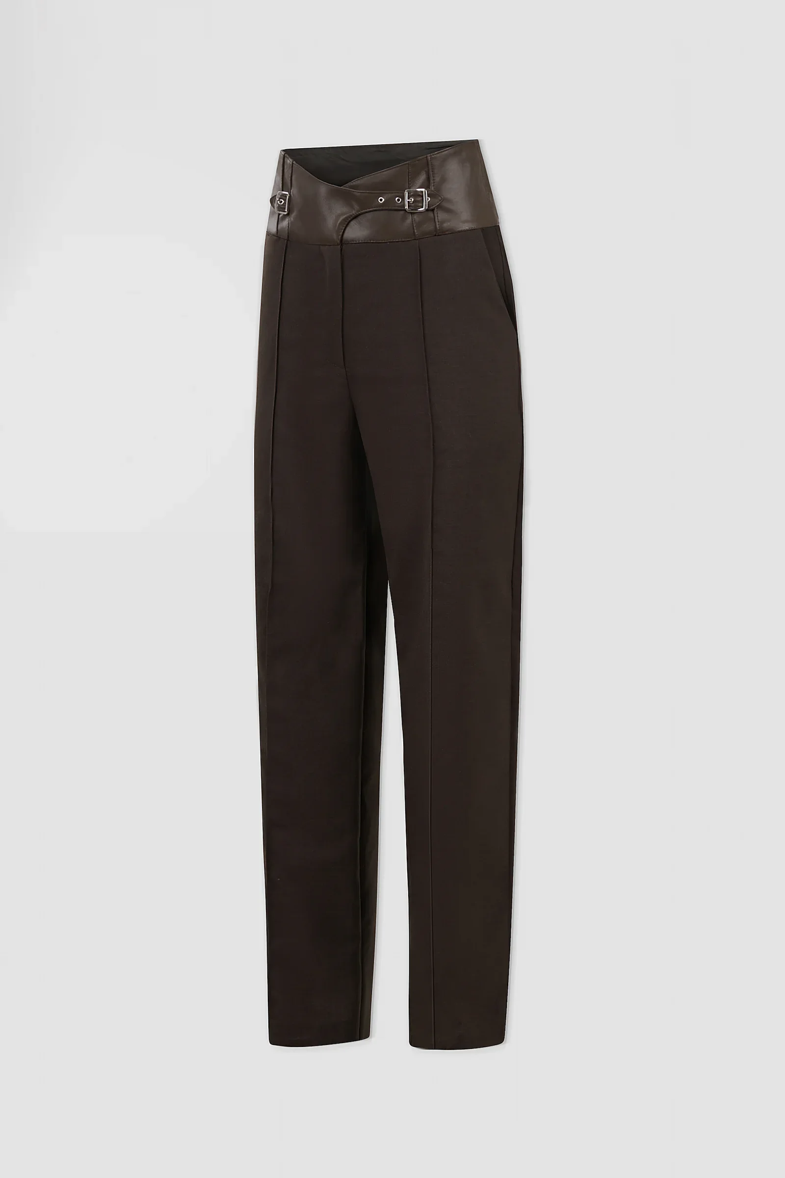 Three-quarter view of ARAKHNE chocolate wool and leather trousers showing the crossover waistband, buckle detailing and straight-leg tailoring.