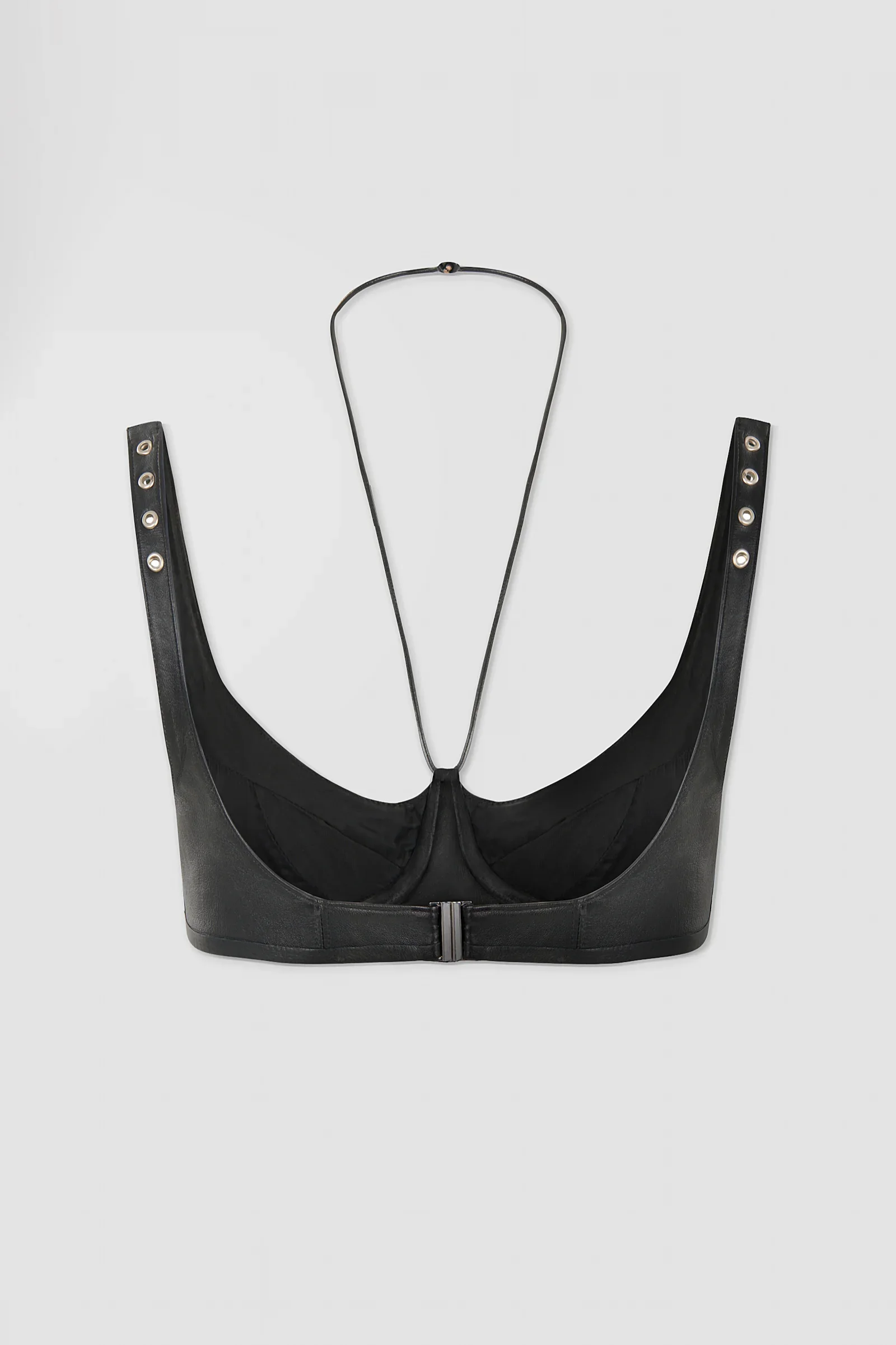 Back: Back view of ARAKHNE's black leather bralette showing its curved construction, metal clasp fastening, eyelet straps and delicate halterneck detail.