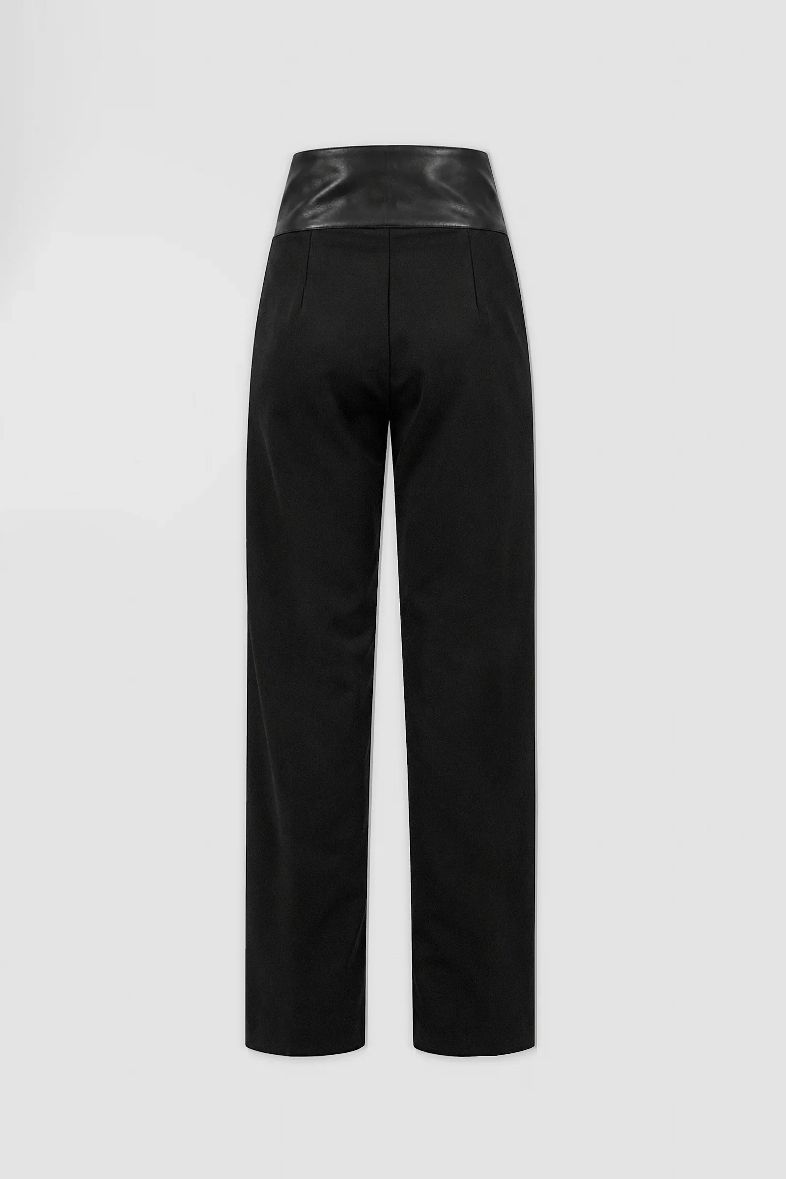 Three-quarter: Three-quarter view of ARAKHNE black wool and leather trousers showing the crossover waistband, buckle detailing and straight-leg tailoring.