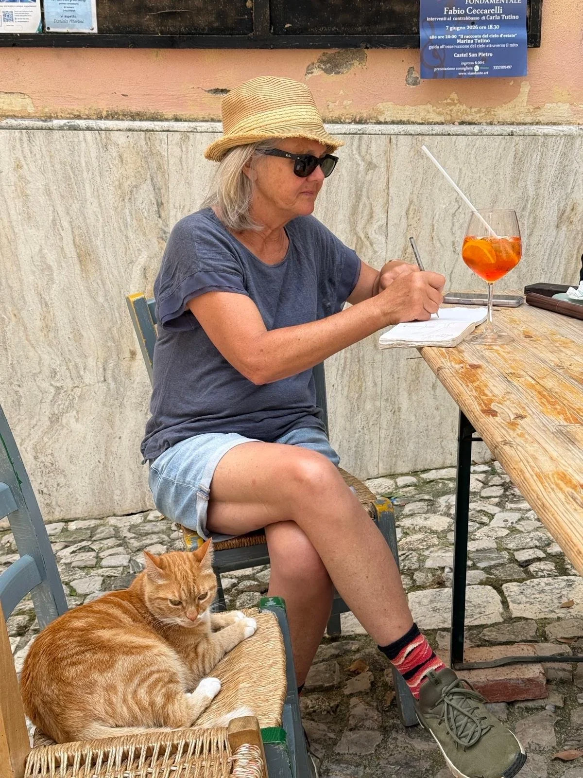 Charlotte at the outdoor table writing in a notebook. 
