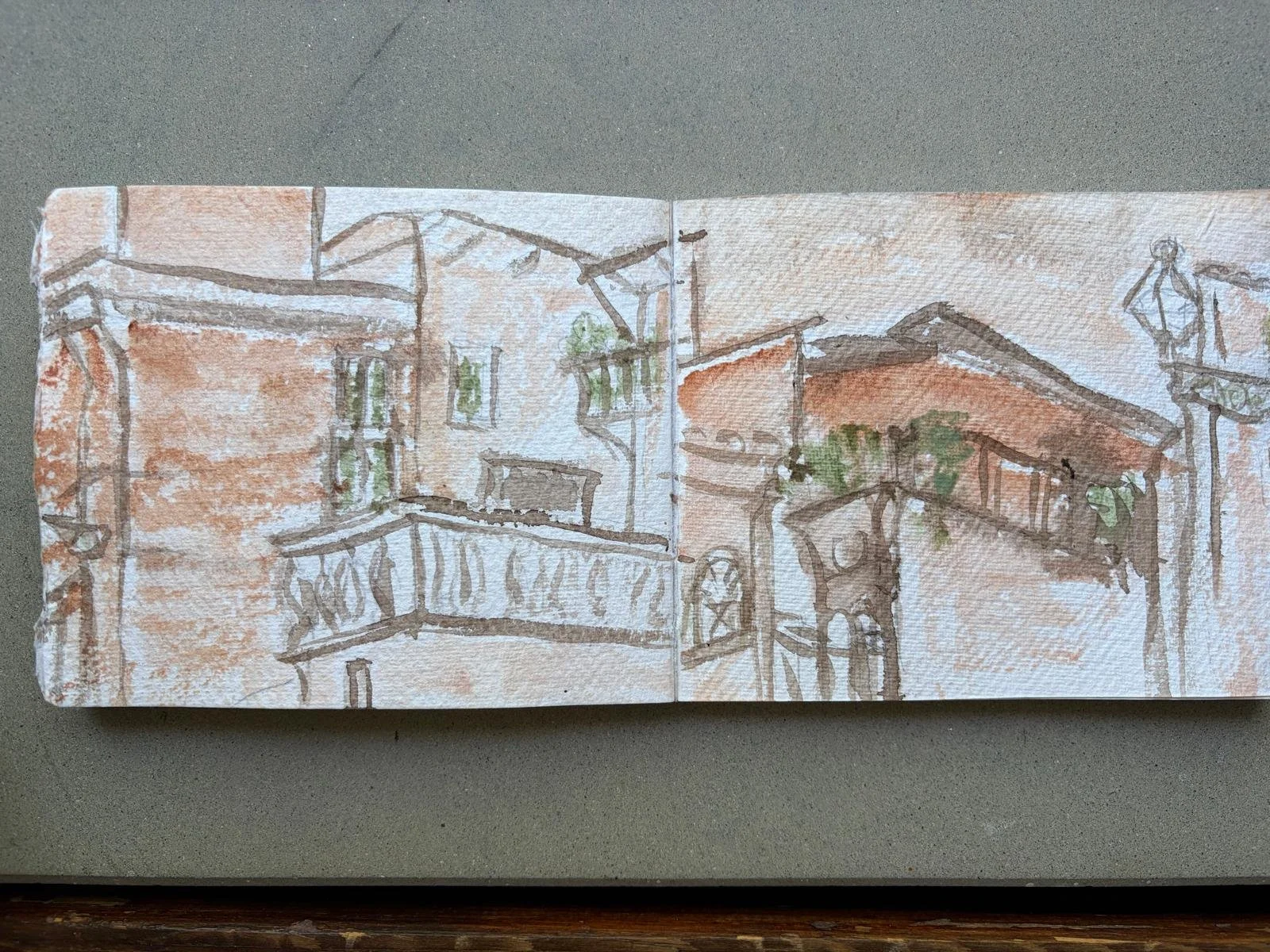 Sketch of a building with multiple balconies, windows, and rooftops, with some greenery, rendered with light brown, gray, and green colors from  Charlotte Andrew Art Retreat in the Sabine Hills, Italy.