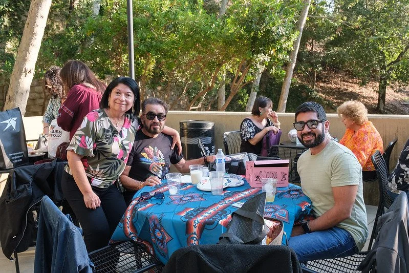 Group of people dining outdoors at the annual Boleros De Noche show at the Ford, with trees in the background.