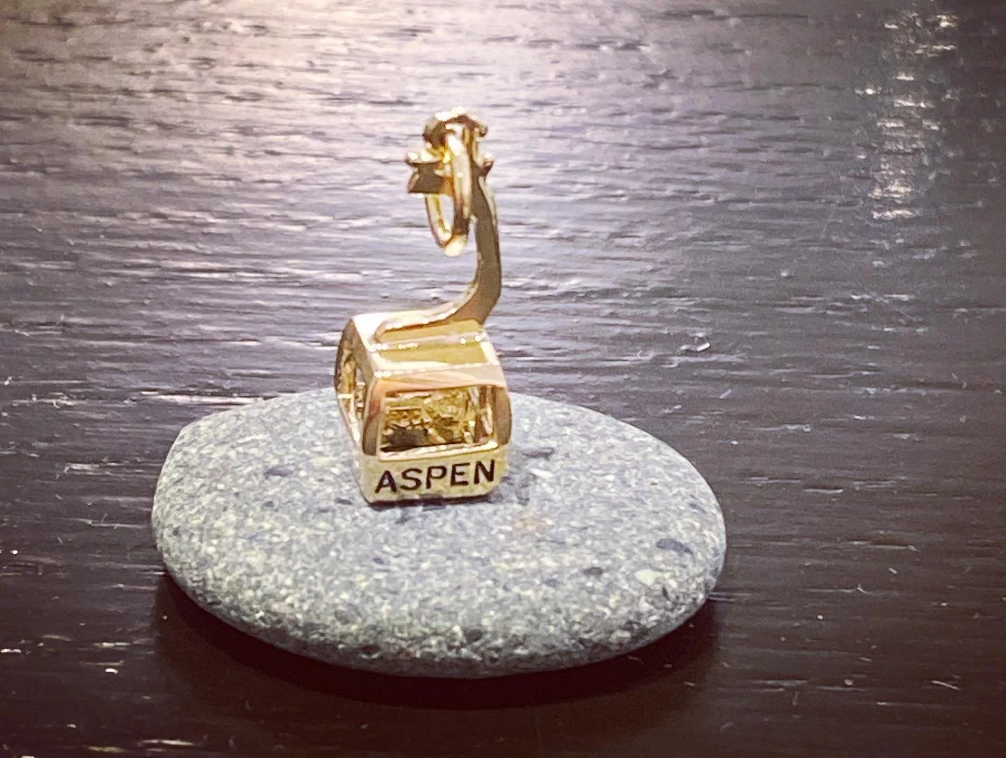 Gold Aspen charm displayed on a stone at The Aspen Hive