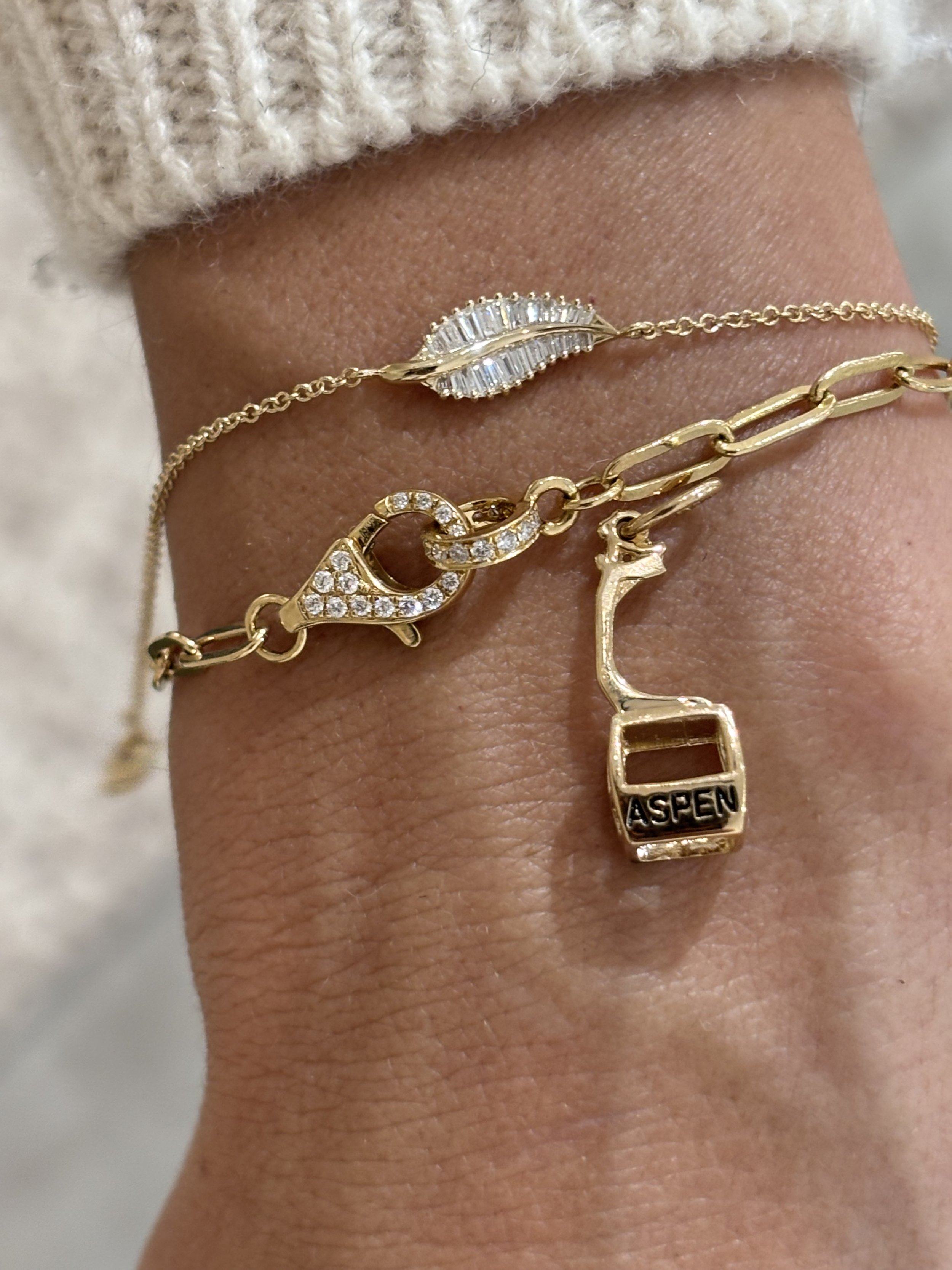 Layered gold bracelets with an Aspen gondola charm at The Aspen Hive in Aspen