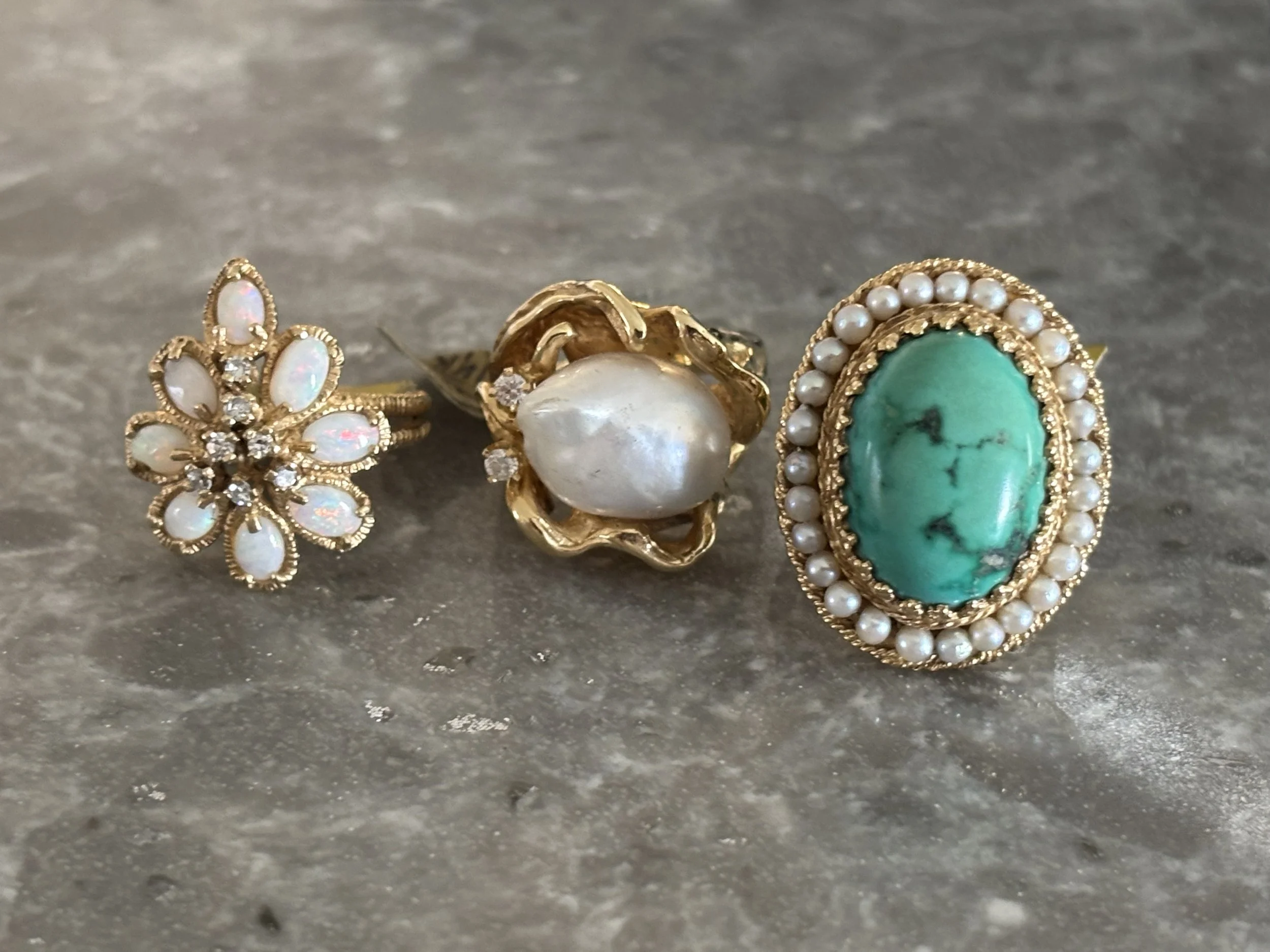 Three statement rings featuring colorful gemstones and pearls