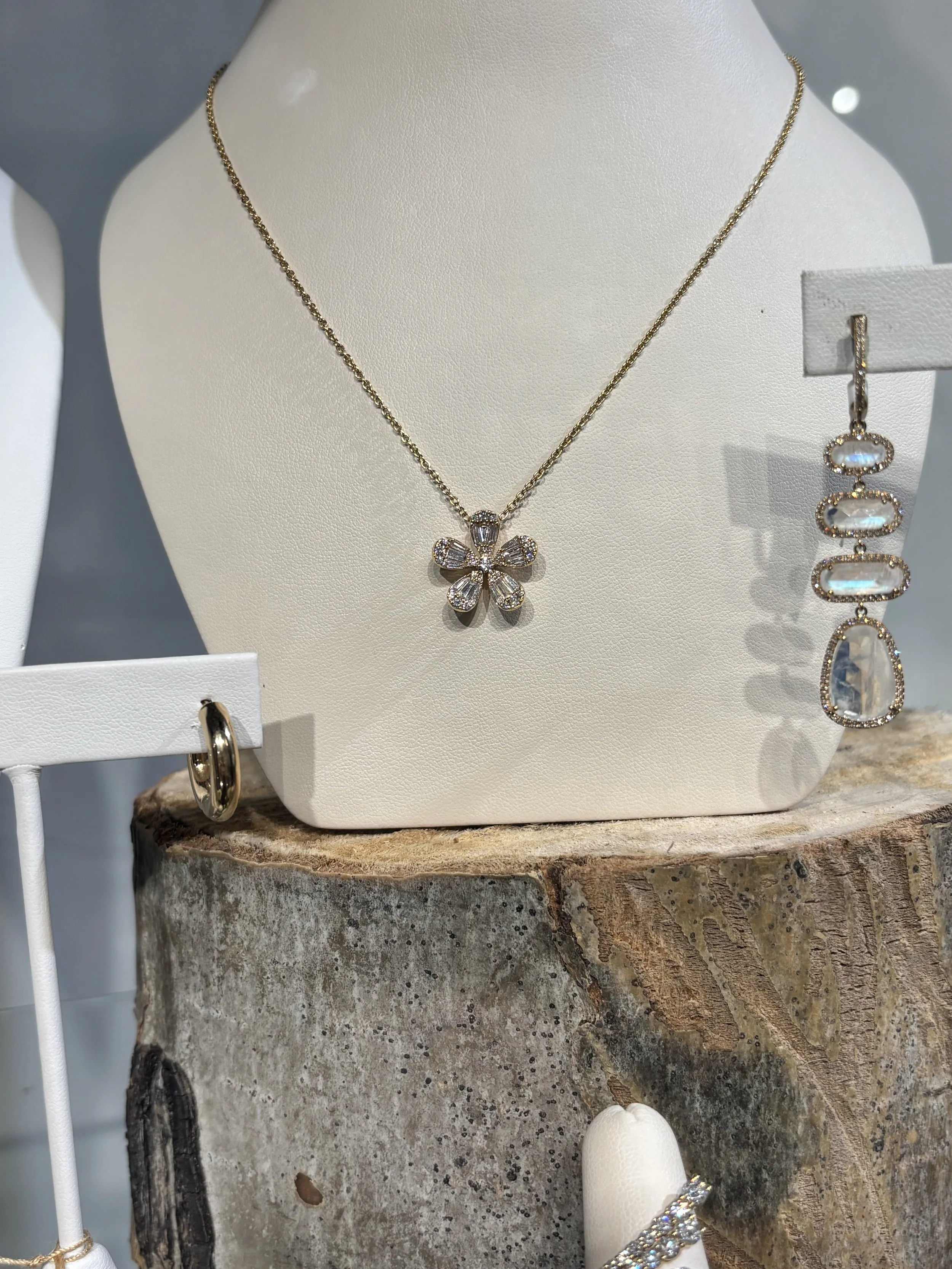 Gold and diamond flower necklace and moonstone earrings displayed at The Aspen Hive in Aspen