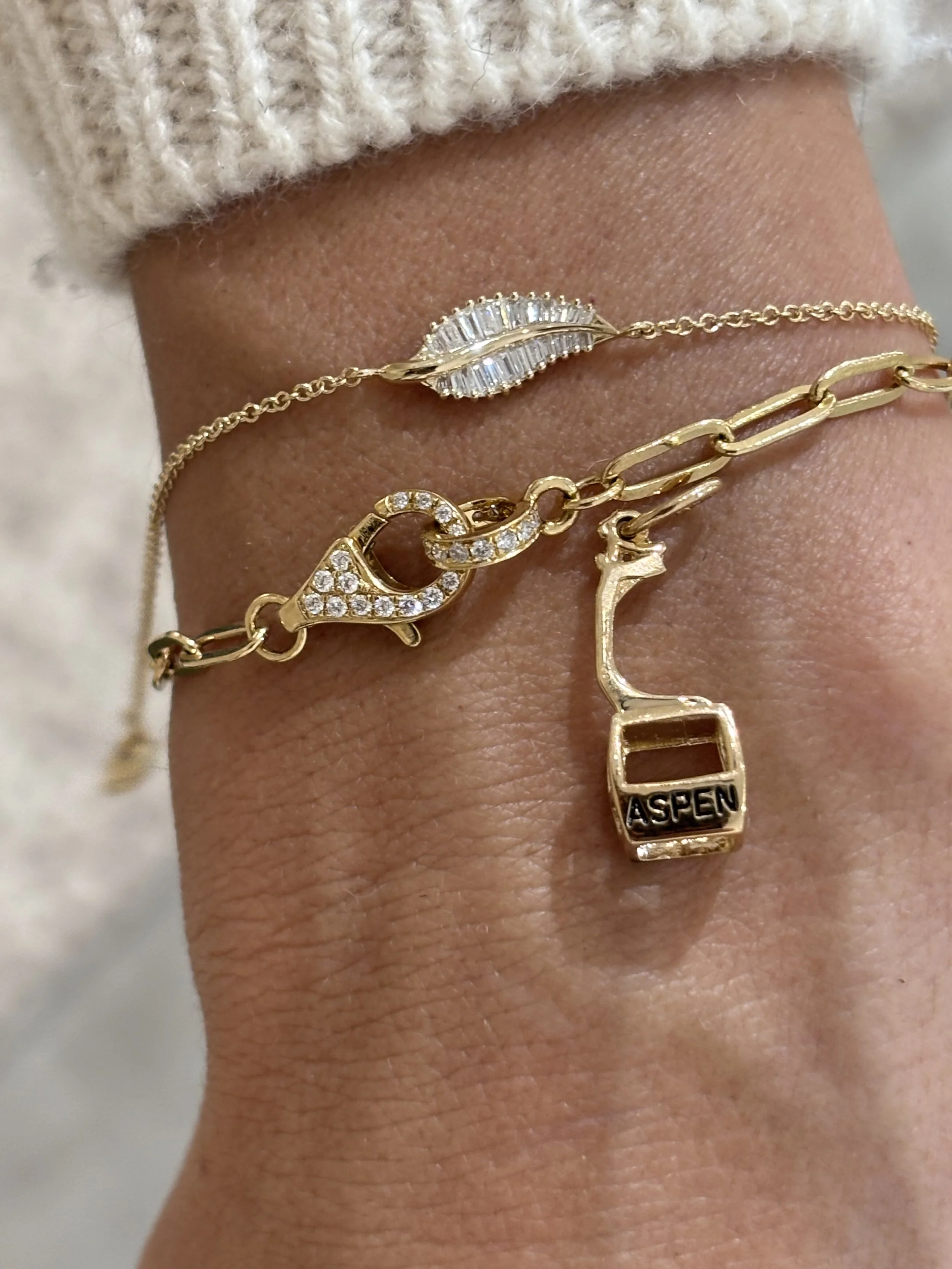 Gold bracelets with charms, including an Aspen charm and an aspen leaf charm