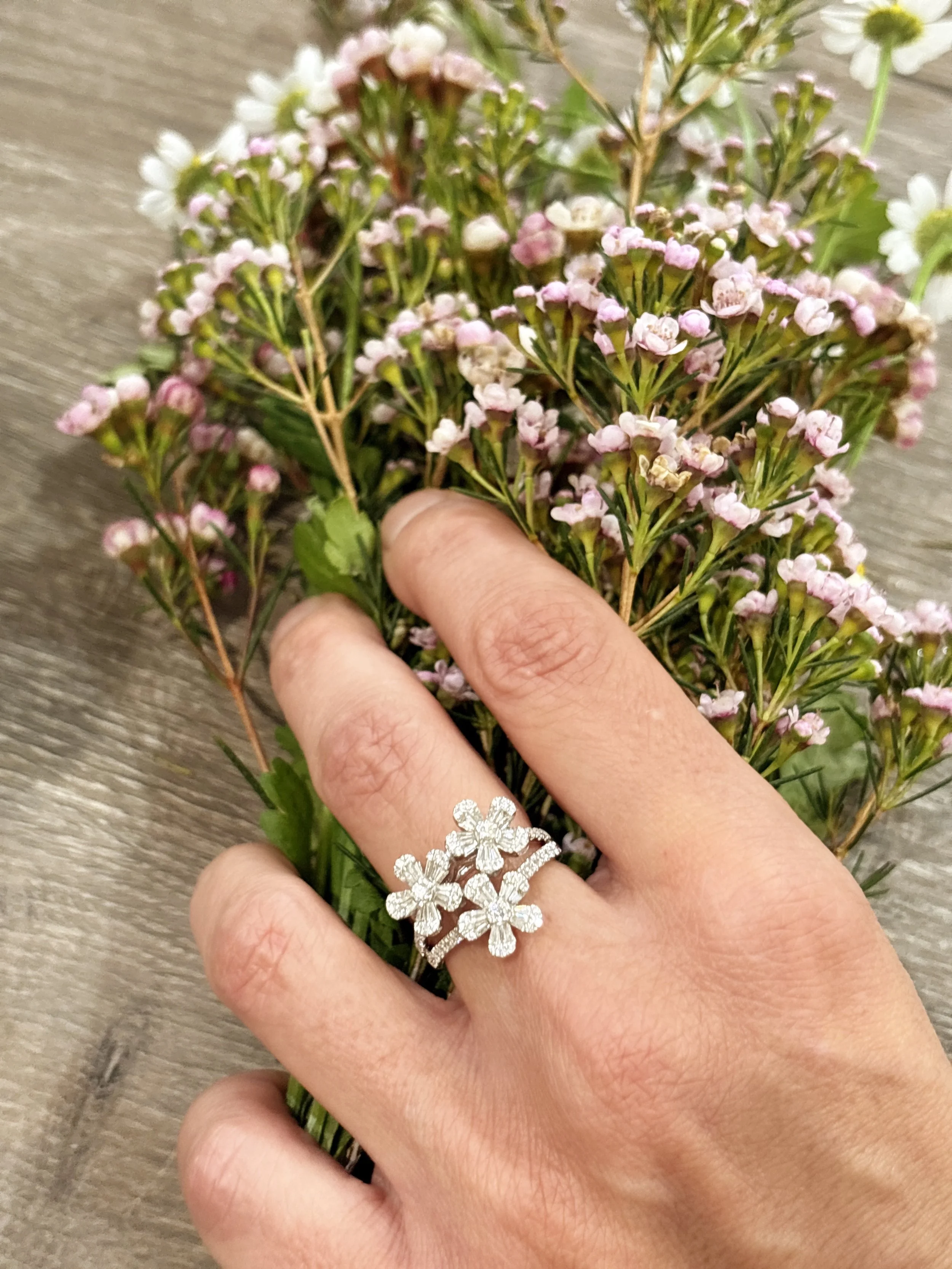 Close-up of a hand holding pink and white flowers with a silver flower-shaped ring at The Aspen Hive