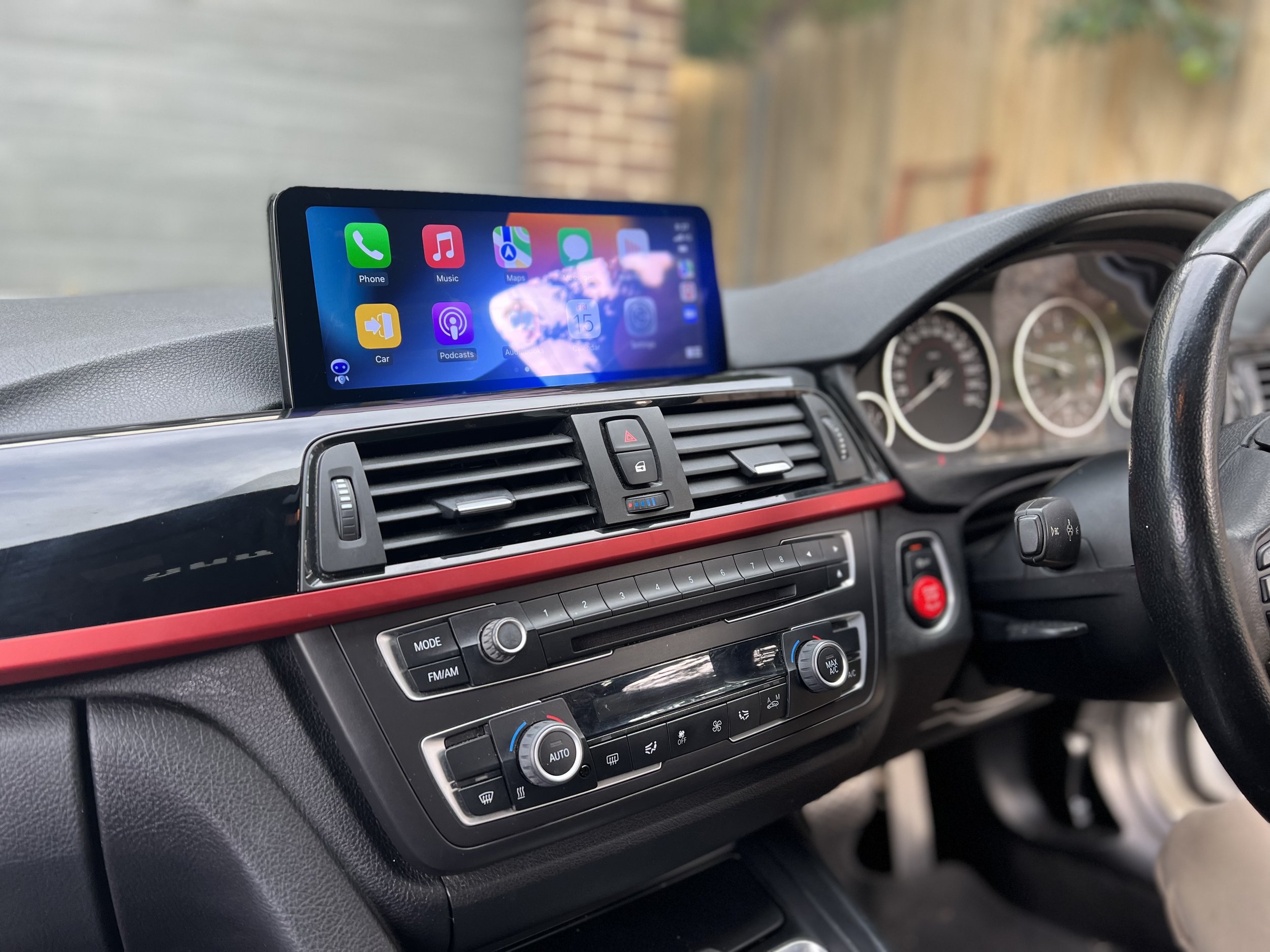 Inside a car dashboard with an iPhone mounted showing various app icons on the screen.