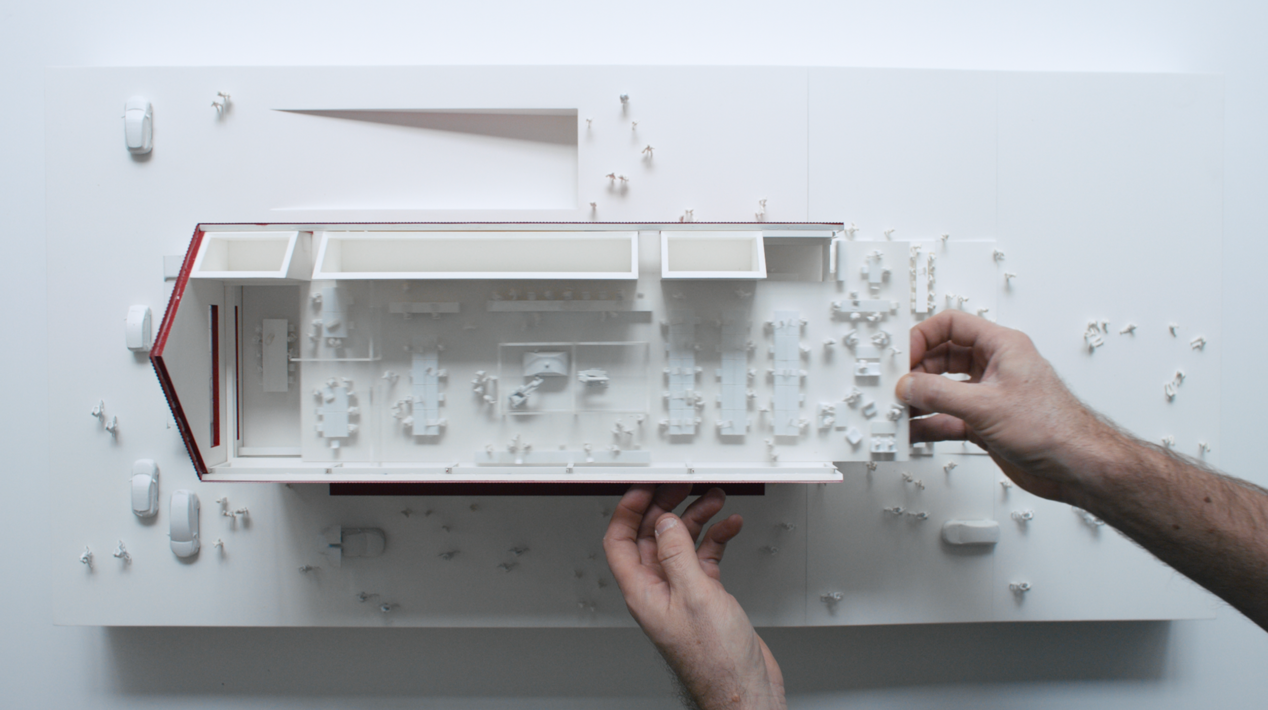 Hands adjusting an architectural scale model during filming for a branded development documentary focused on design process and spatial planning.