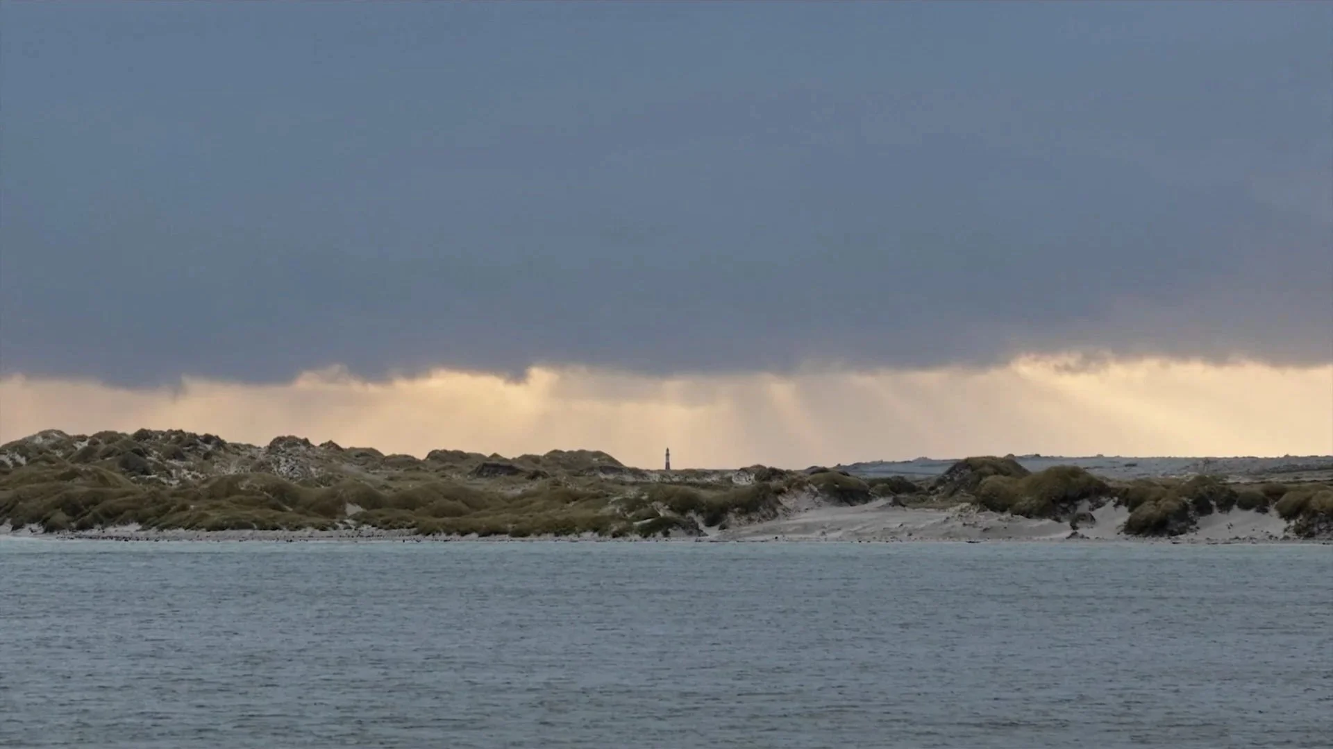Falkland Islands coastline under a stormy South Atlantic sky, looking
across sheltered water toward distant shores — filmed for Connecting Falklands