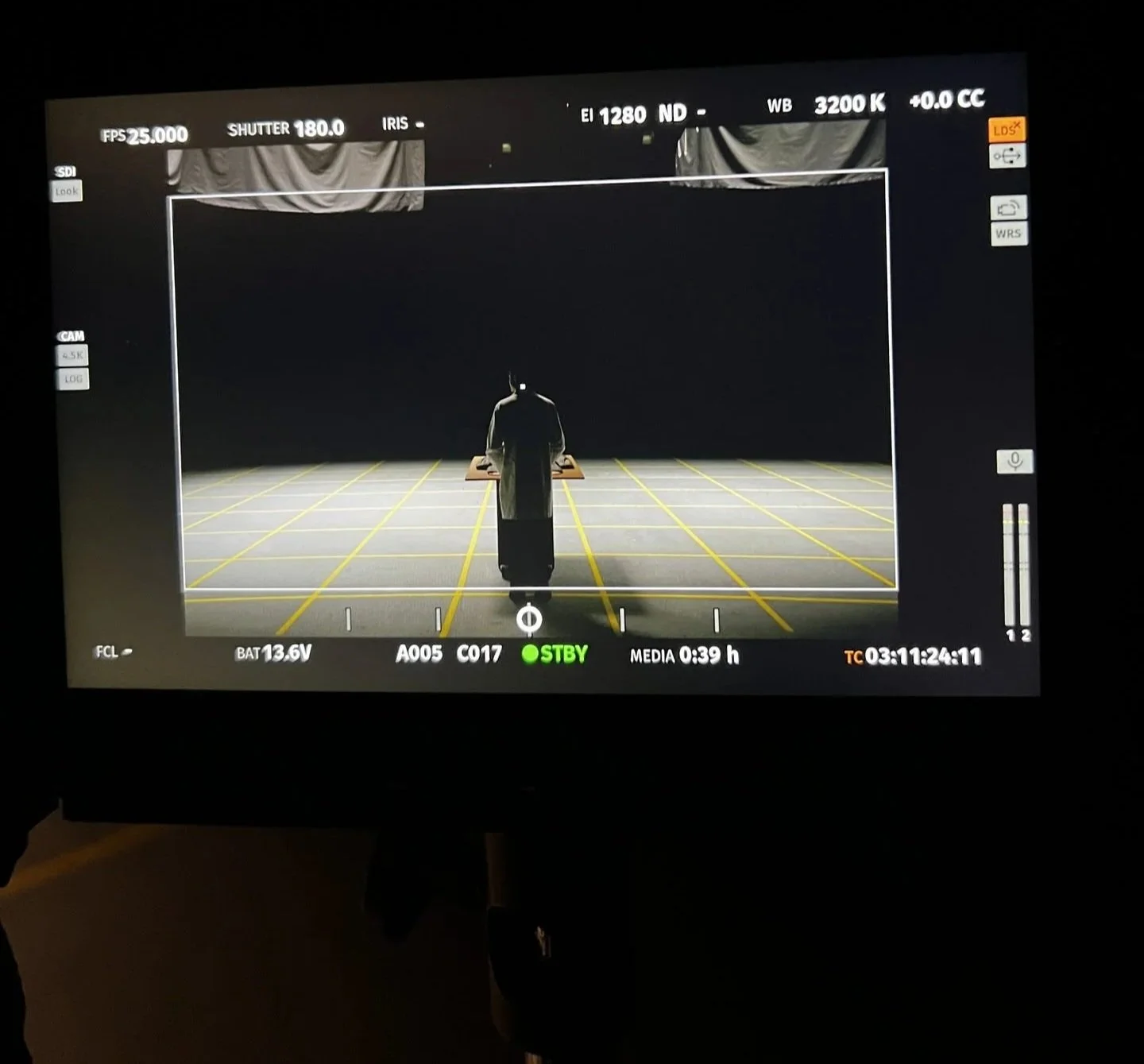 SmallHD monitor showing model in Marfa Stance long coat on yellow-gridded studio floor,
fashion DOP James Dougan