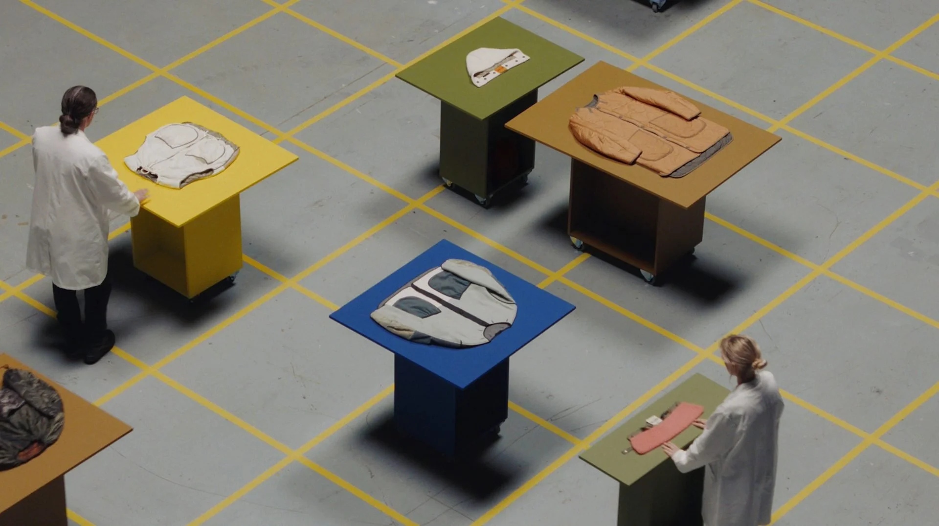 Marfa Stance film still: overhead wide of performers in white coats placing garments on
plinths, x Isabel & Helen, DOP James Dougan