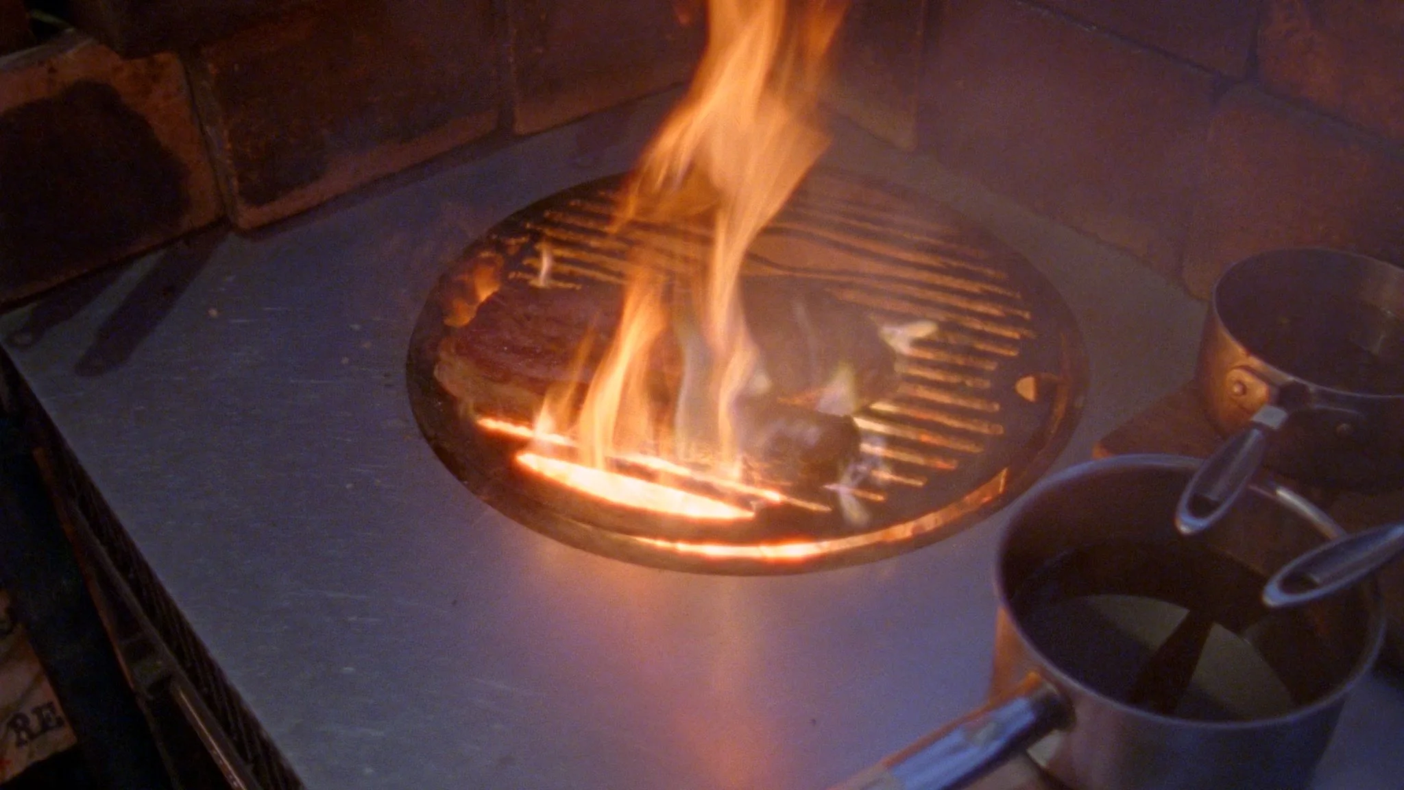 Chef cooking over open fire at Brat Restaurant in London, filmed for a documentary