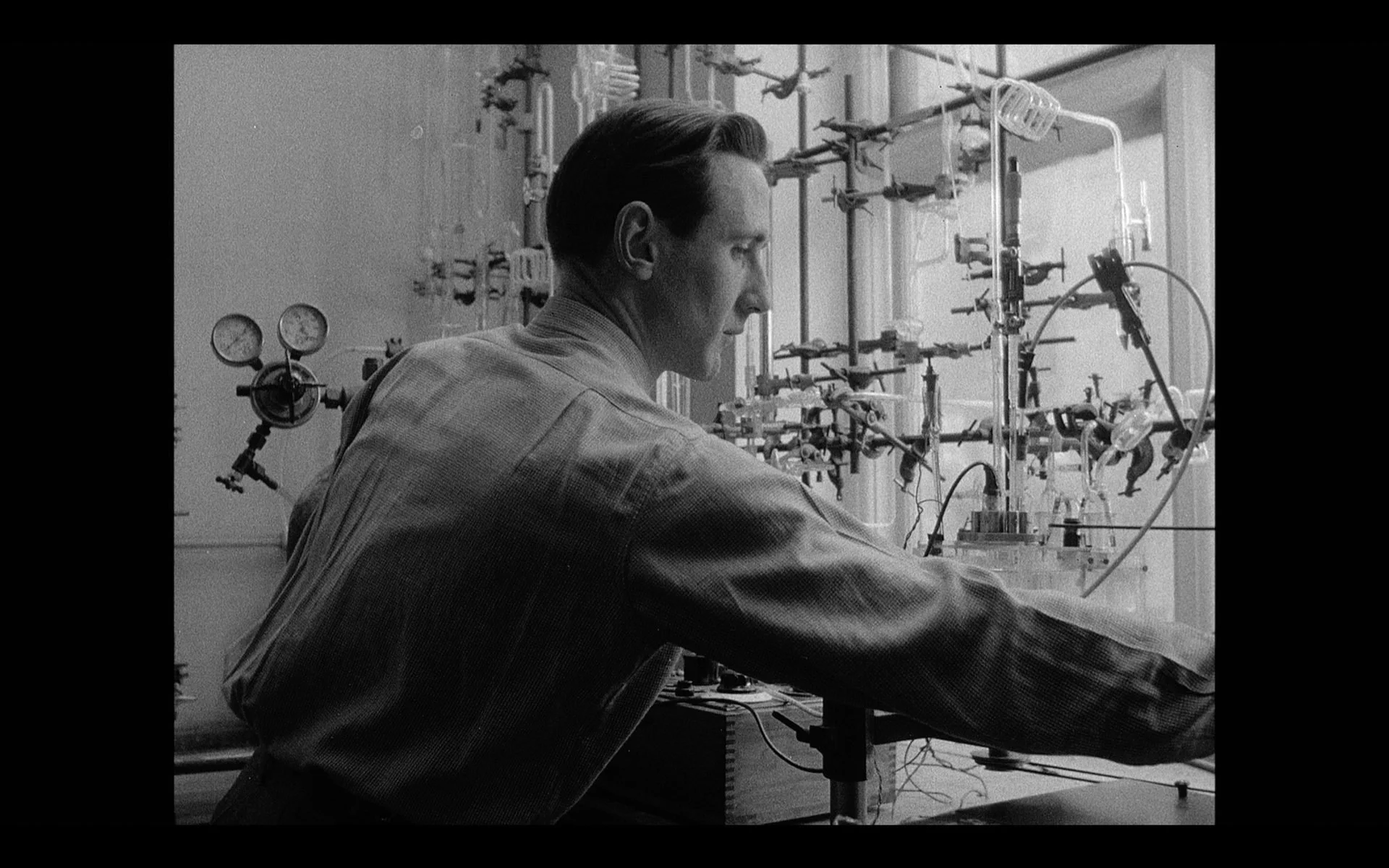 Black and white archive image of a scientist at work, used in a branded architectural documentary to reference research, experimentation, and historical innovation.
