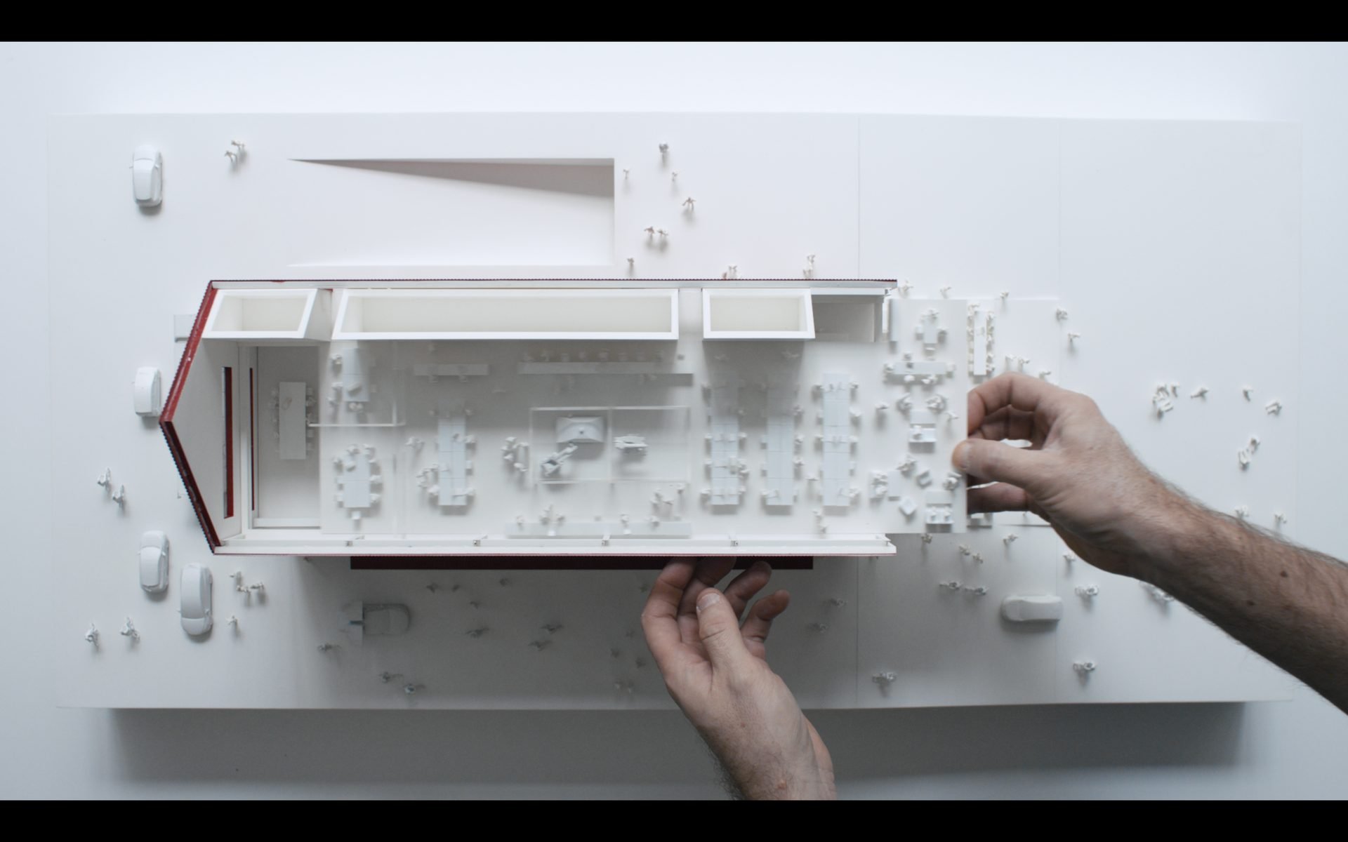 Hands adjusting an architectural scale model during filming for a branded development documentary focused on design process and spatial planning.