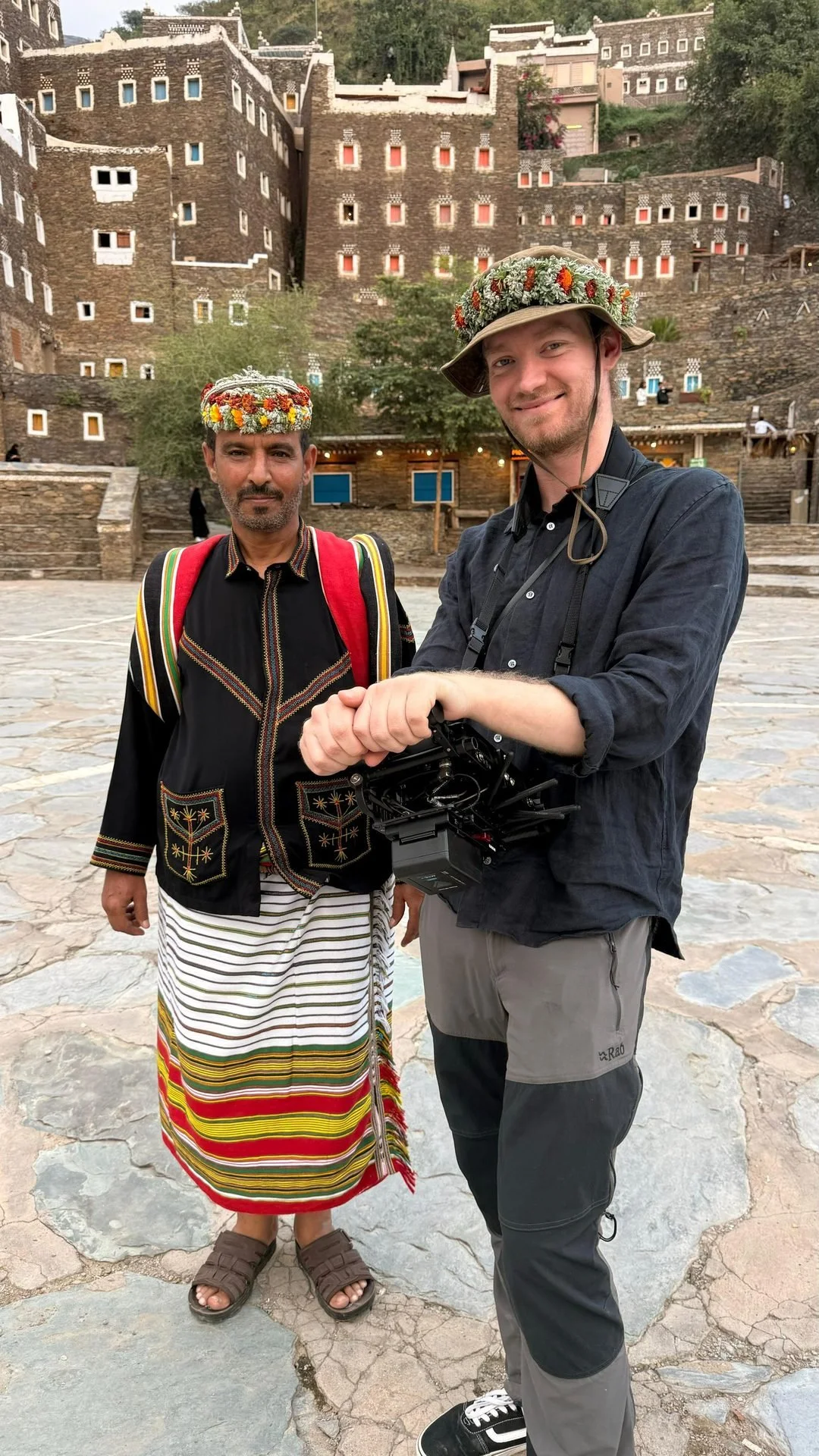 Crew member sharing fist bump with Flower Man at Rijal Almaa heritage village