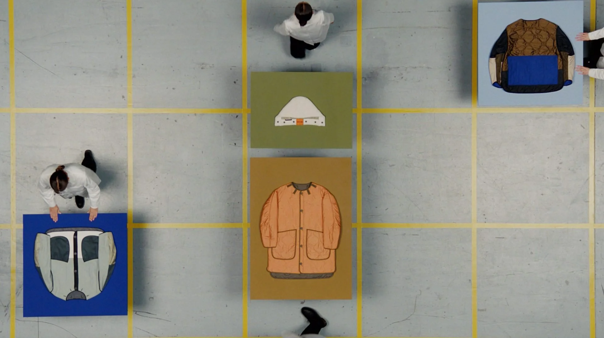 Marfa Stance film still: overhead shot of performers arranging outerwear on coloured plinths
in grid, DOP James Dougan