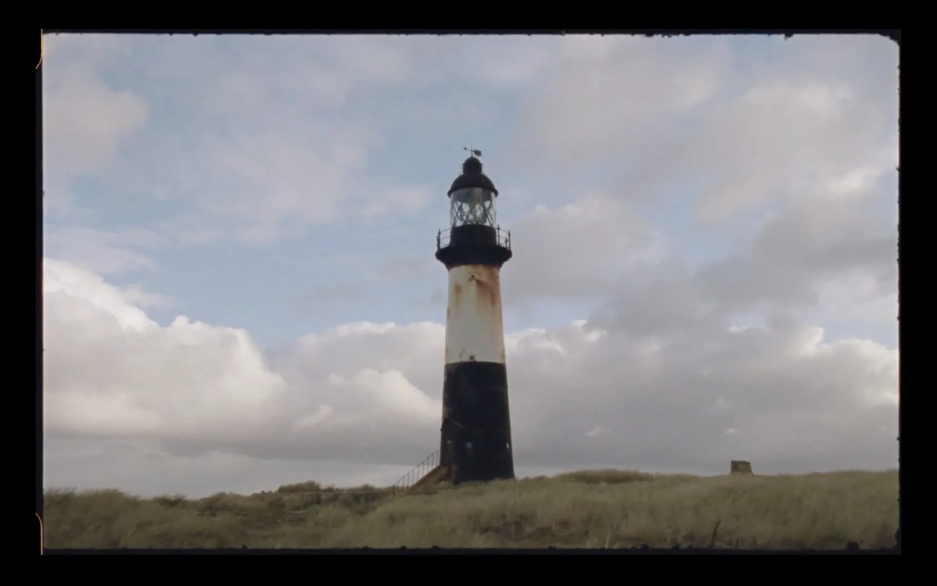 Cape Pembroke lighthouse, black and white striped, standing on sandy
dunes near Stanley, Falkland Islands — film still from Connecting The Falklands