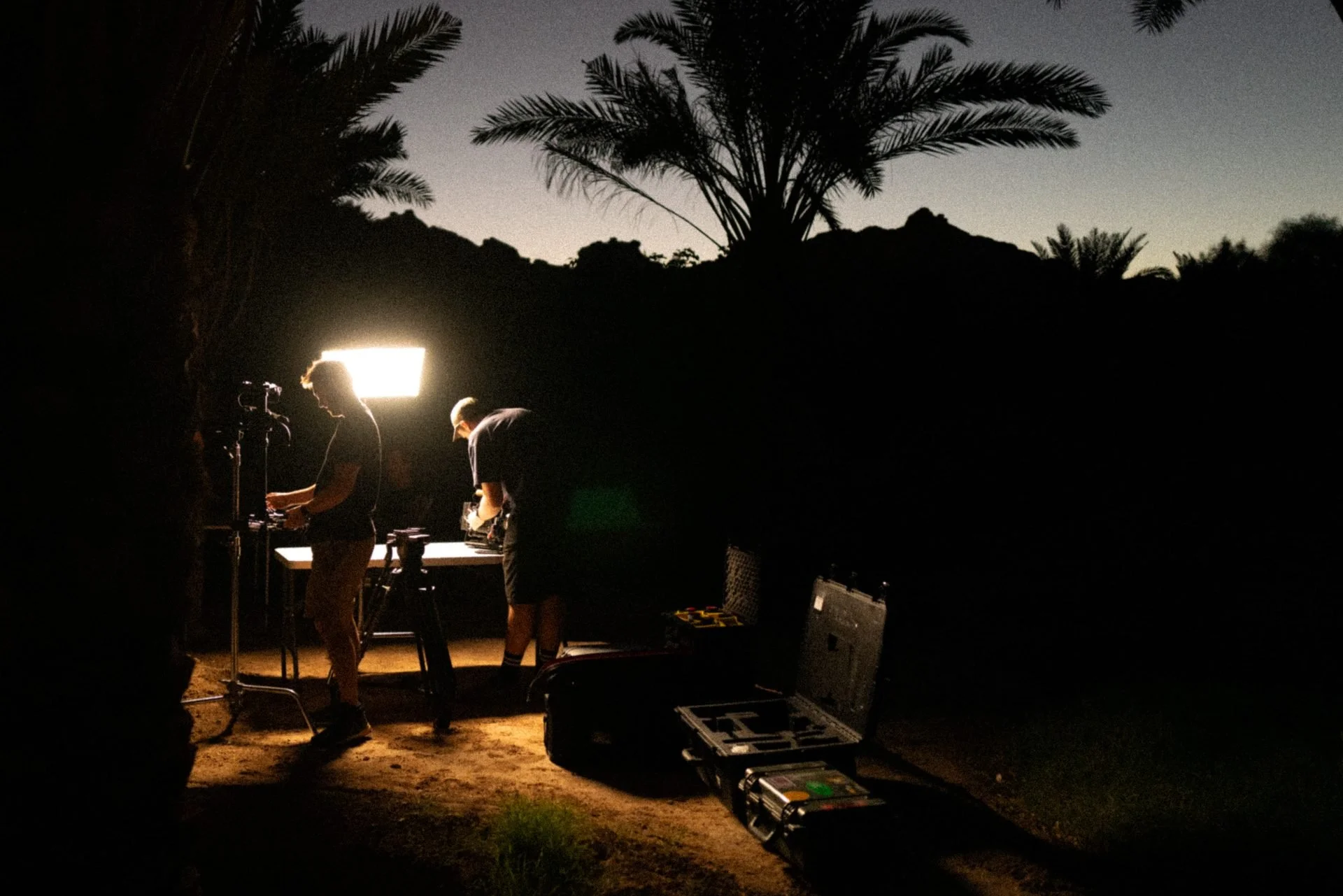 Crew setting up lighting at night beneath oasis palm trees for Evolving Cities