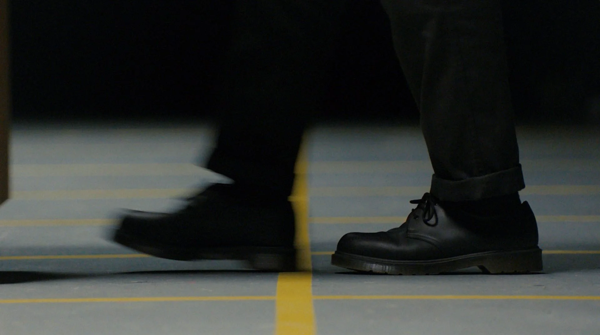 Marfa Stance film still: close-up of feet walking across yellow-gridded studio floor with motion
blur, DOP James Dougan