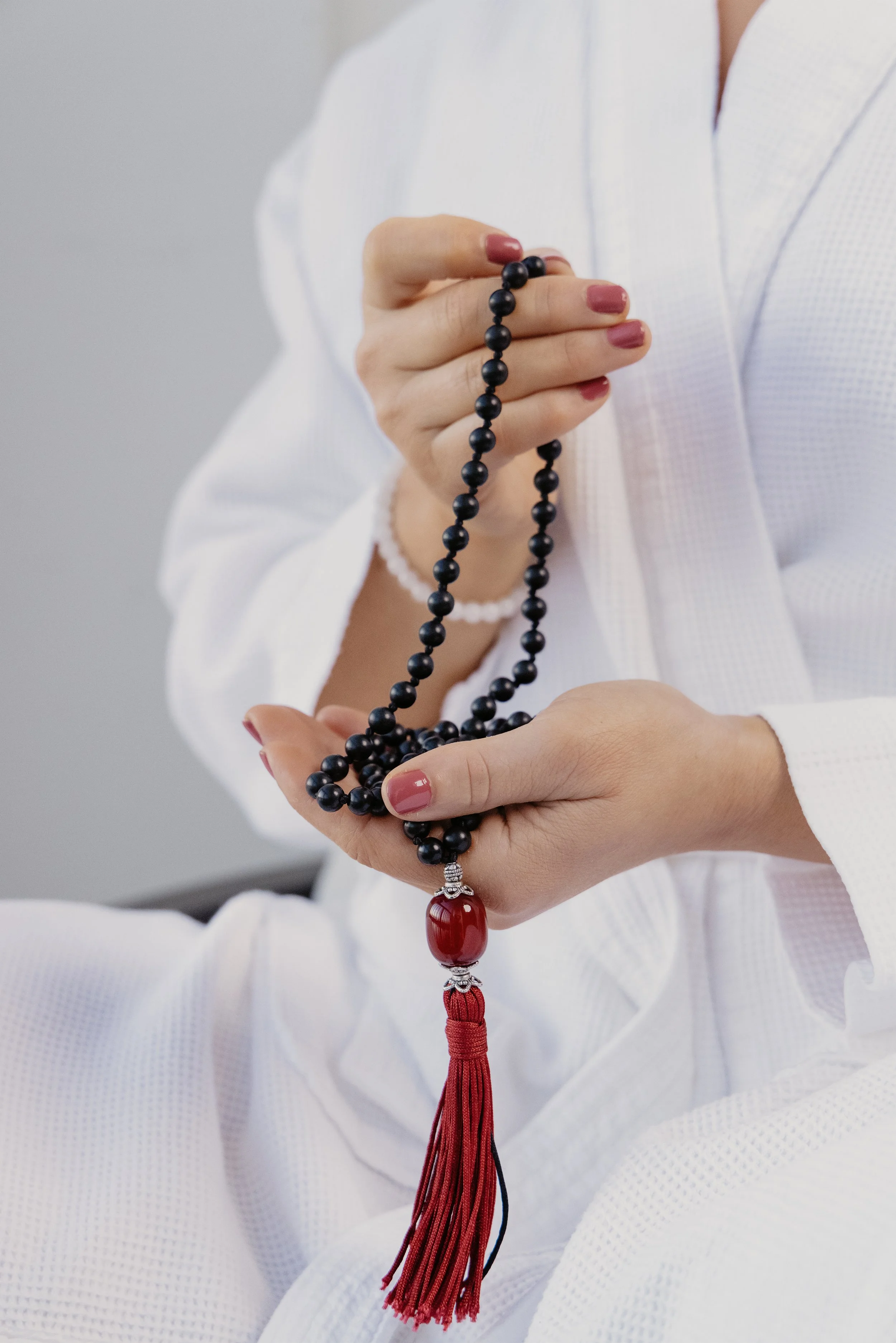Two hands holding mala beads