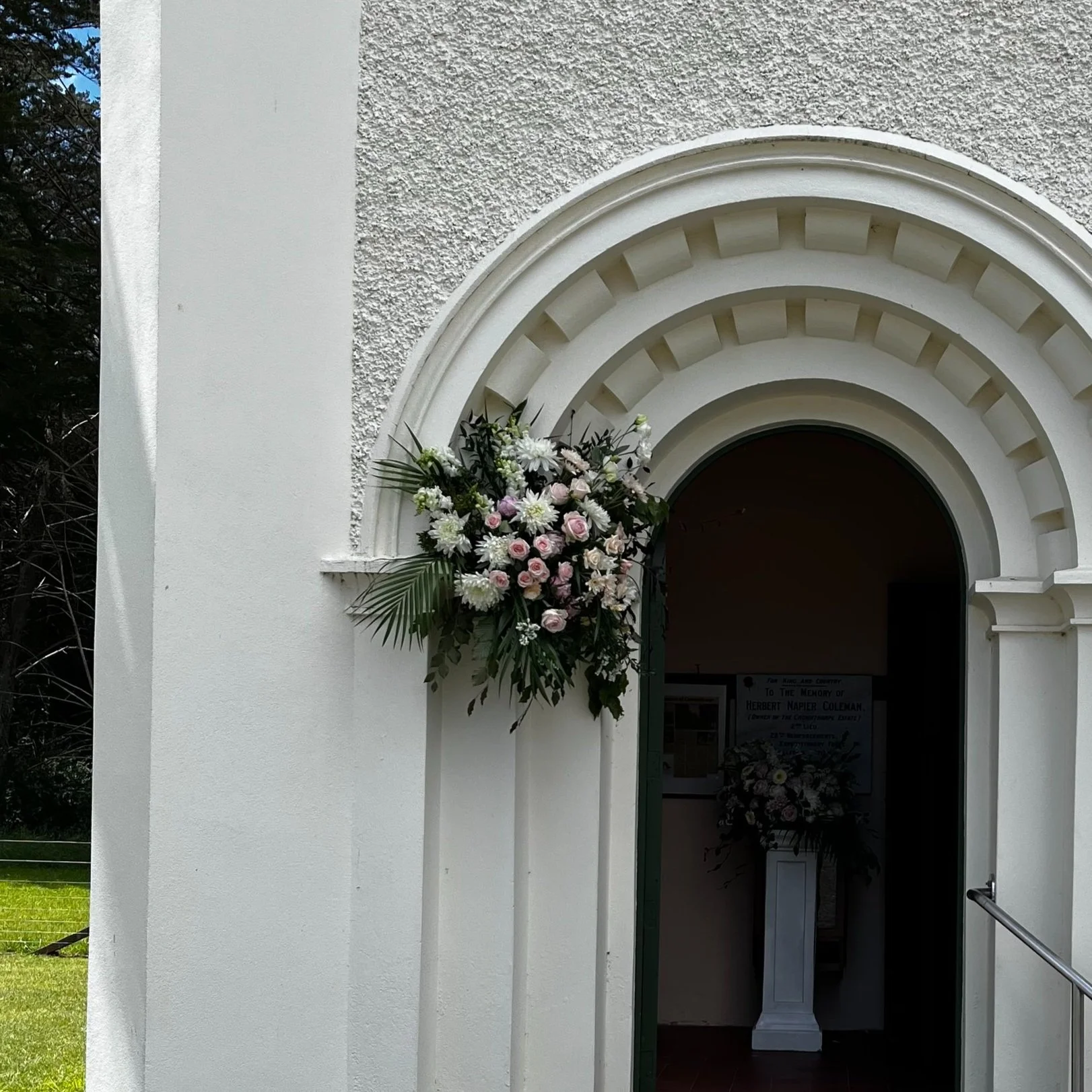 Flower arrangement on the wall of a white church or building with an arched entrance