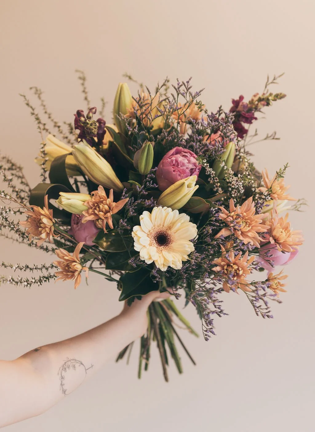 A beautiful bouquet of flowers being help up by the florist