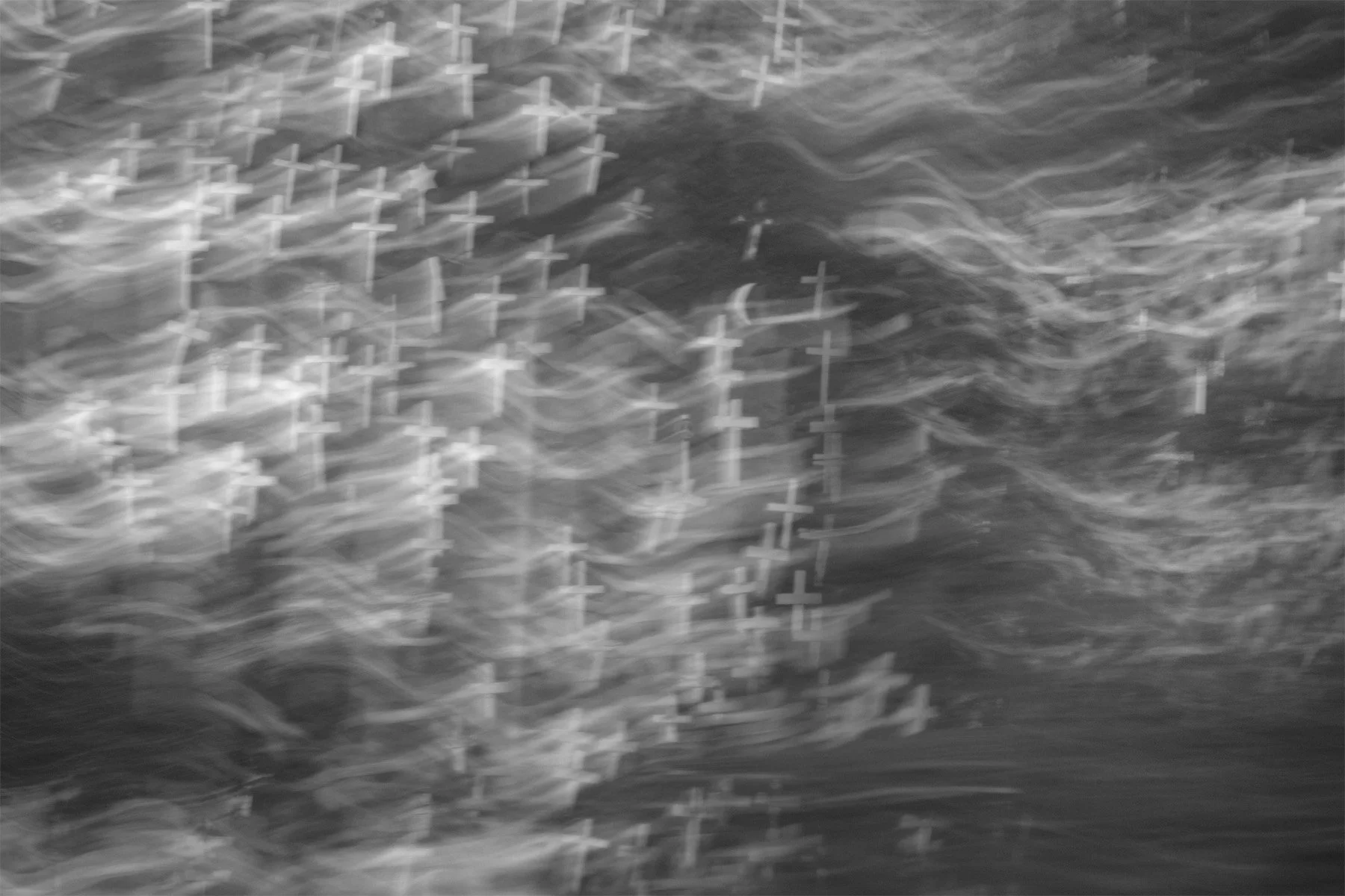 black and white photograph created with intentional camera movement featuring dozens of crosses in a flowing wave of light and shadow.