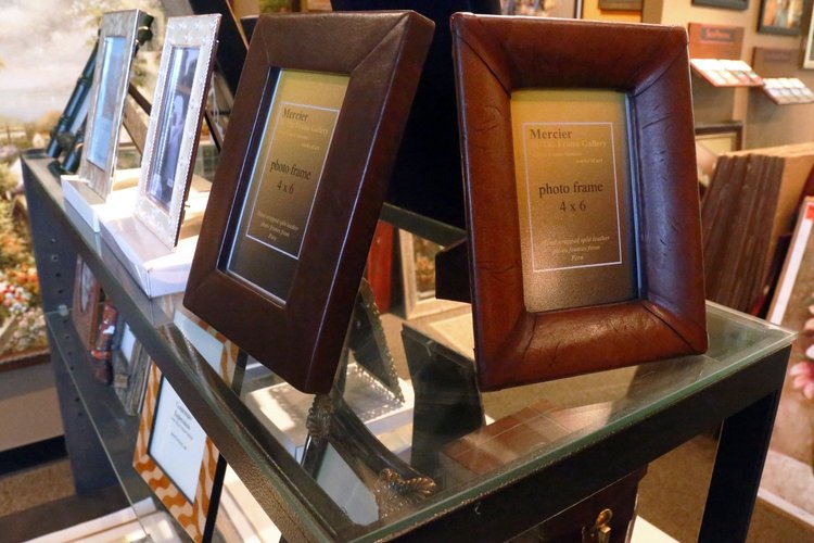 Leather and silver photo frames on a glass shelf in the gift area of The Frame Gallery in San Antonio