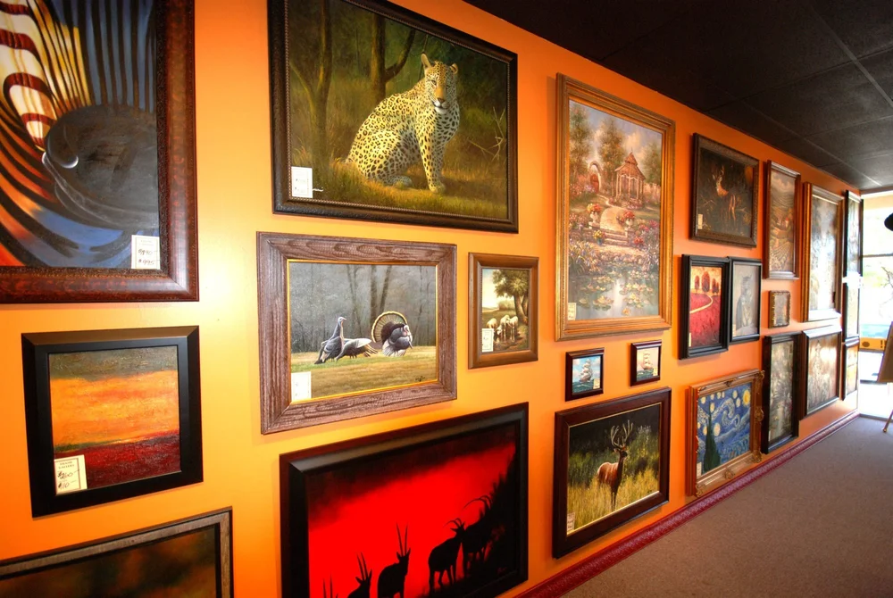Framed paintings hanging on the wall at The Frame Gallery in San Antonio