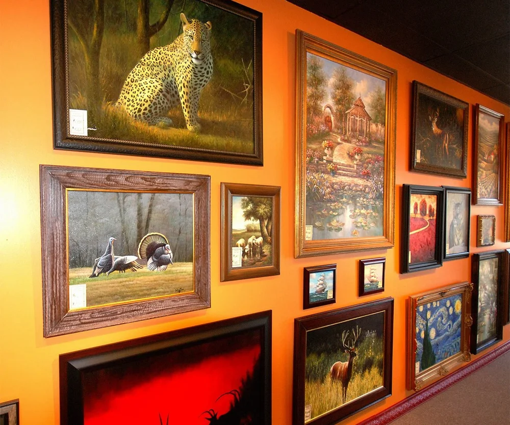 Hand-painted wildlife, garden and ship paintings hang on an orange gallery wall