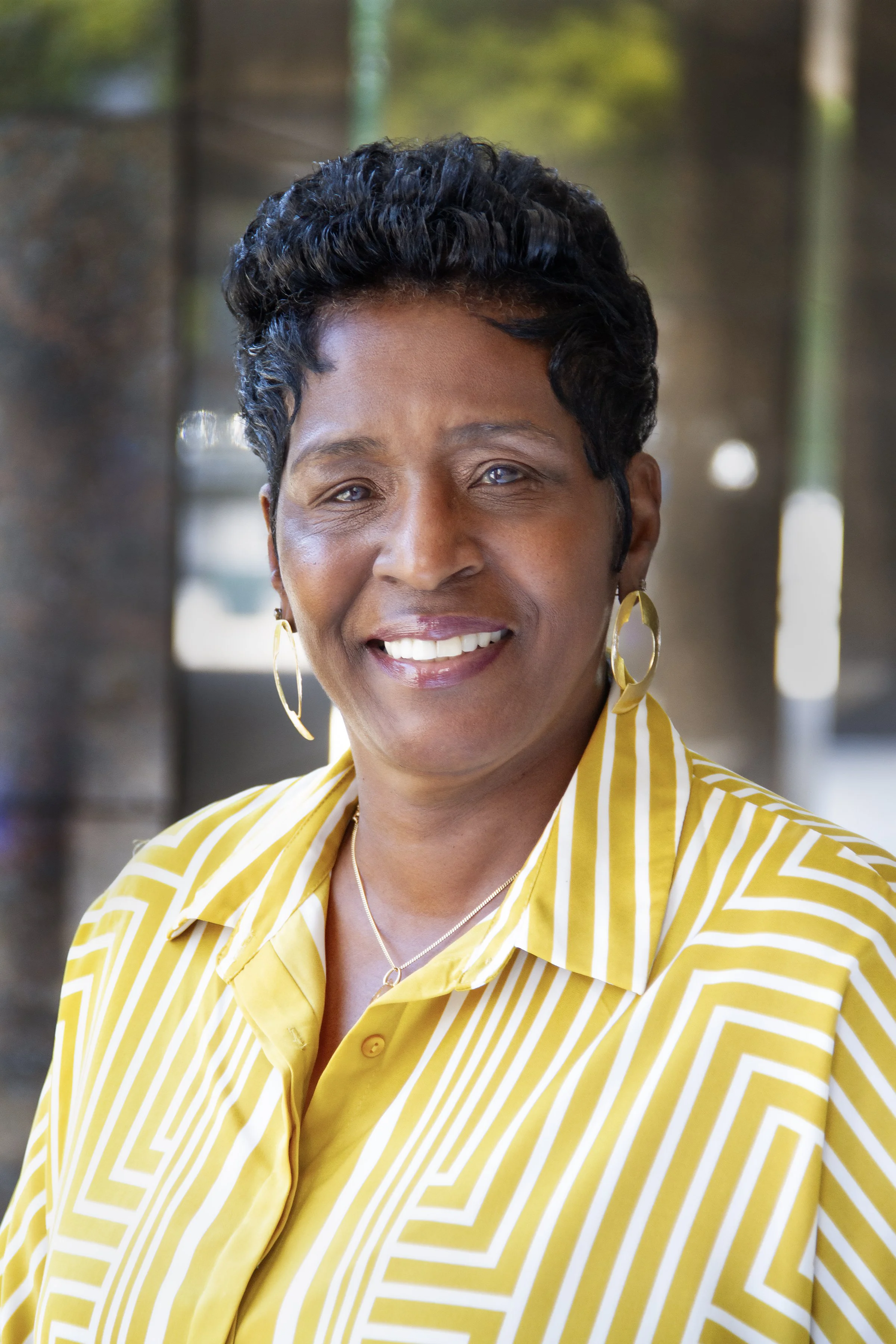 headshot of smiling woman wearing yellow patterned button-down shirt