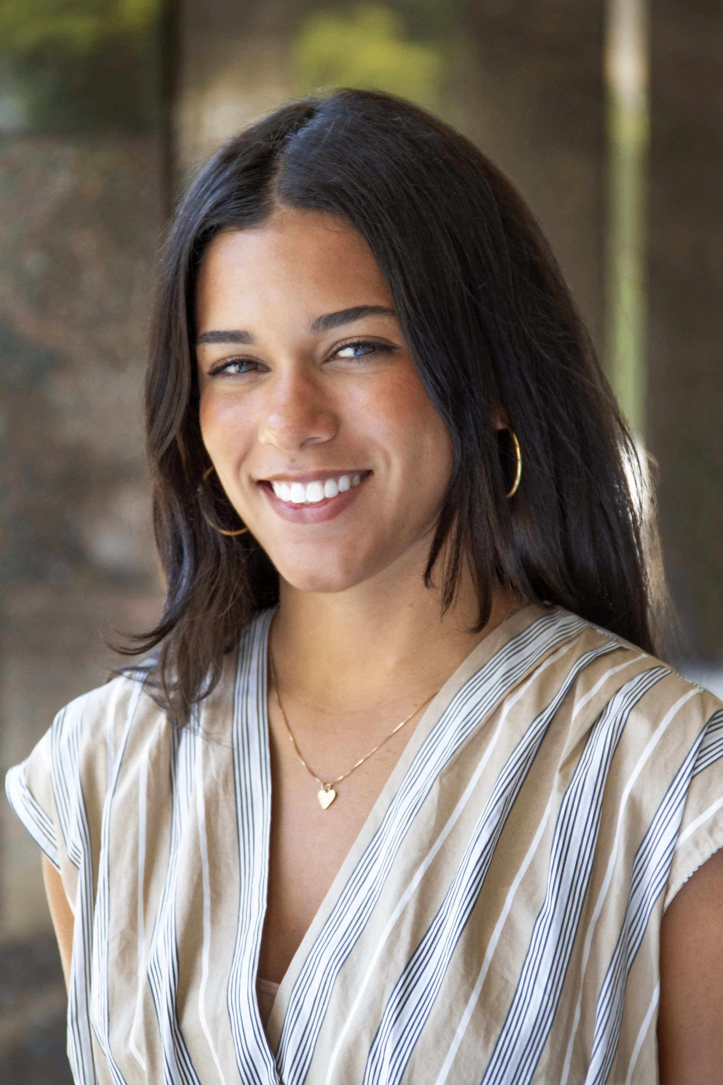 headshot of smiling woman with dark hair and light-striped short sleeve shirt