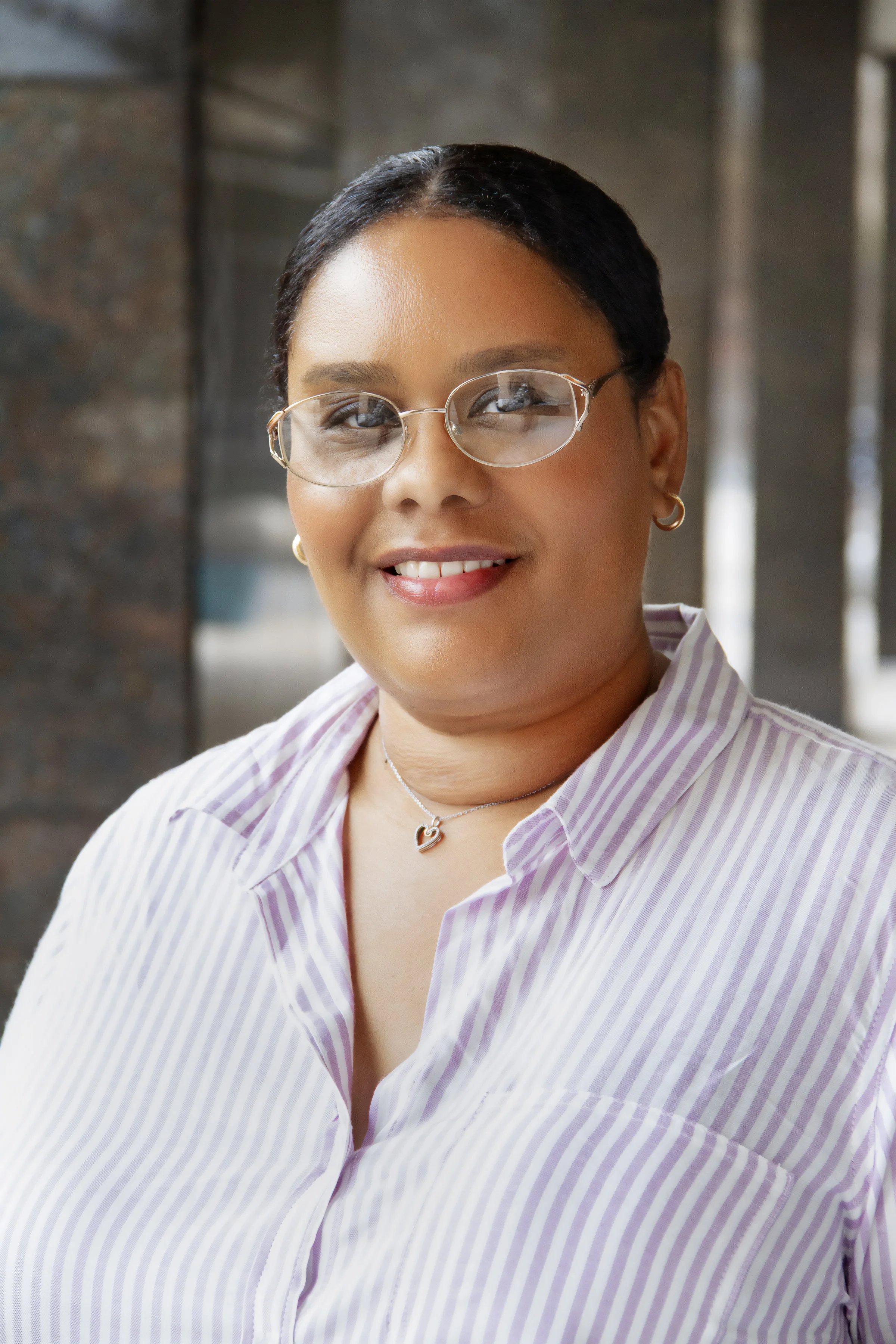 headshot of woman wearing glasses and light striped button-down shirt