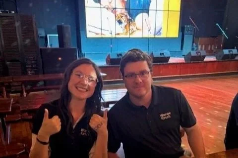 man and woman wearing dark polo shirts seated and posing for photo