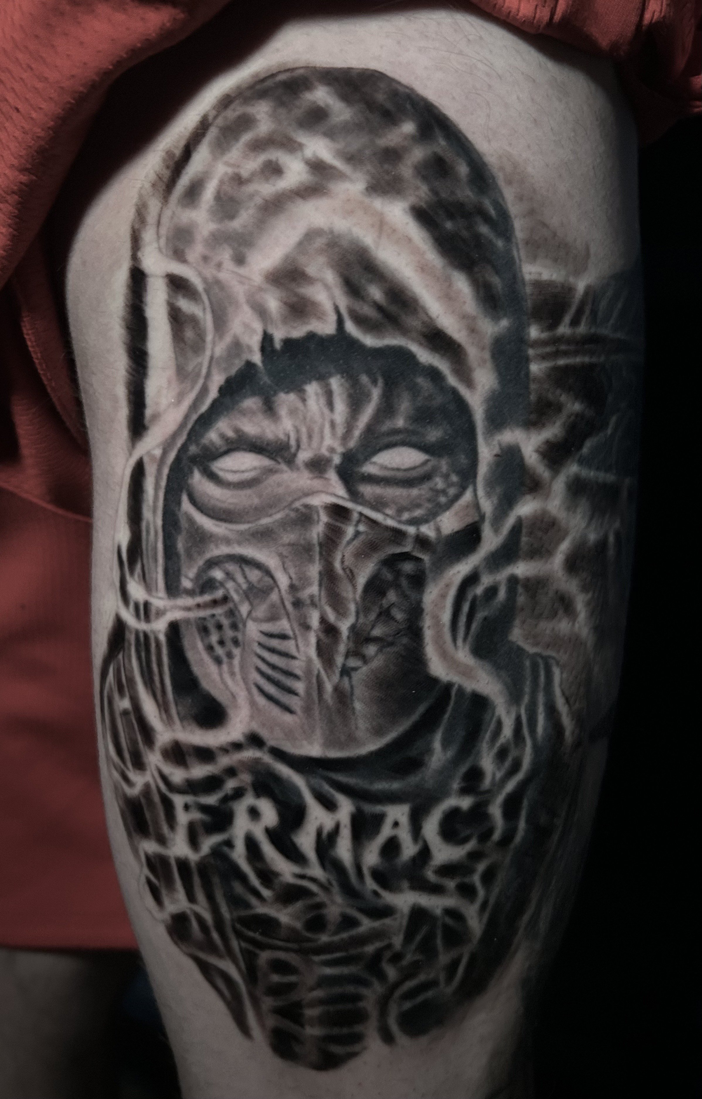Tattoo of a hooded figure with a mask and the word 'ERMAC' on skin. Tattoo by Brett Guerra.