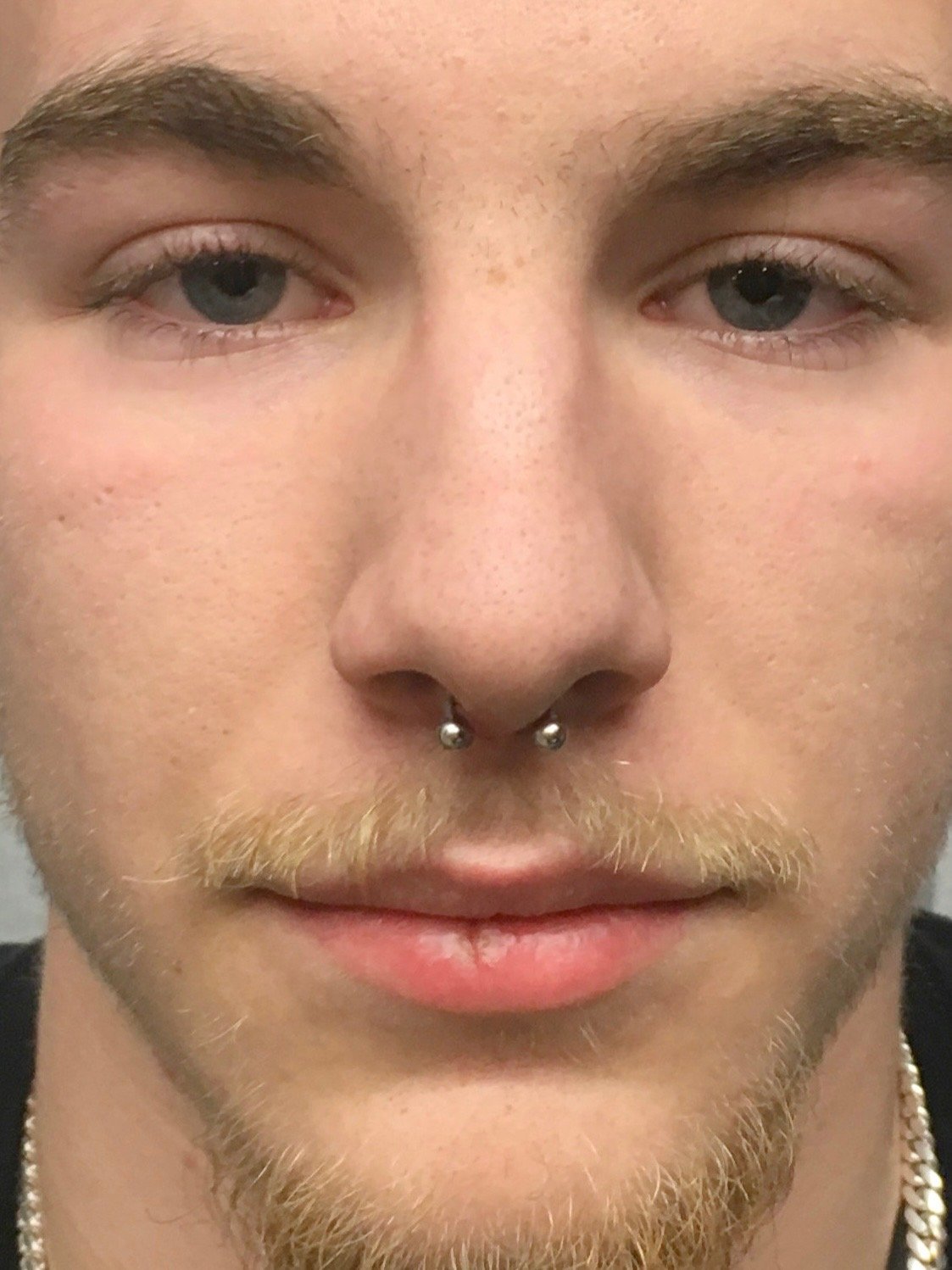 Close-up of a face with a septum piercing and a light mustache and beard. Piercing by Stephanie Guerra.