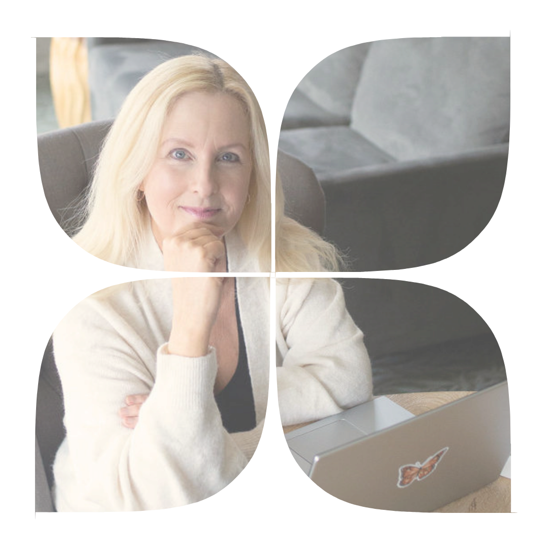 A woman with long blonde hair sitting at a table with a laptop, resting her chin on her hand and looking at the camera.