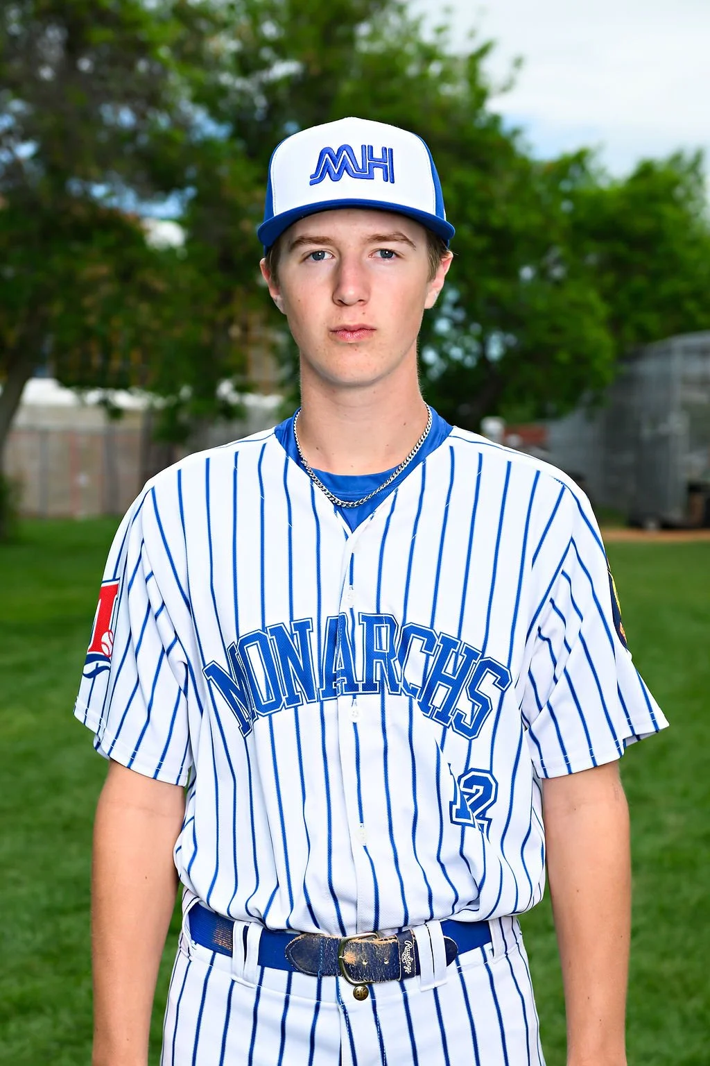 Young man in a blue baseball uniform and cap standing on a baseball field.