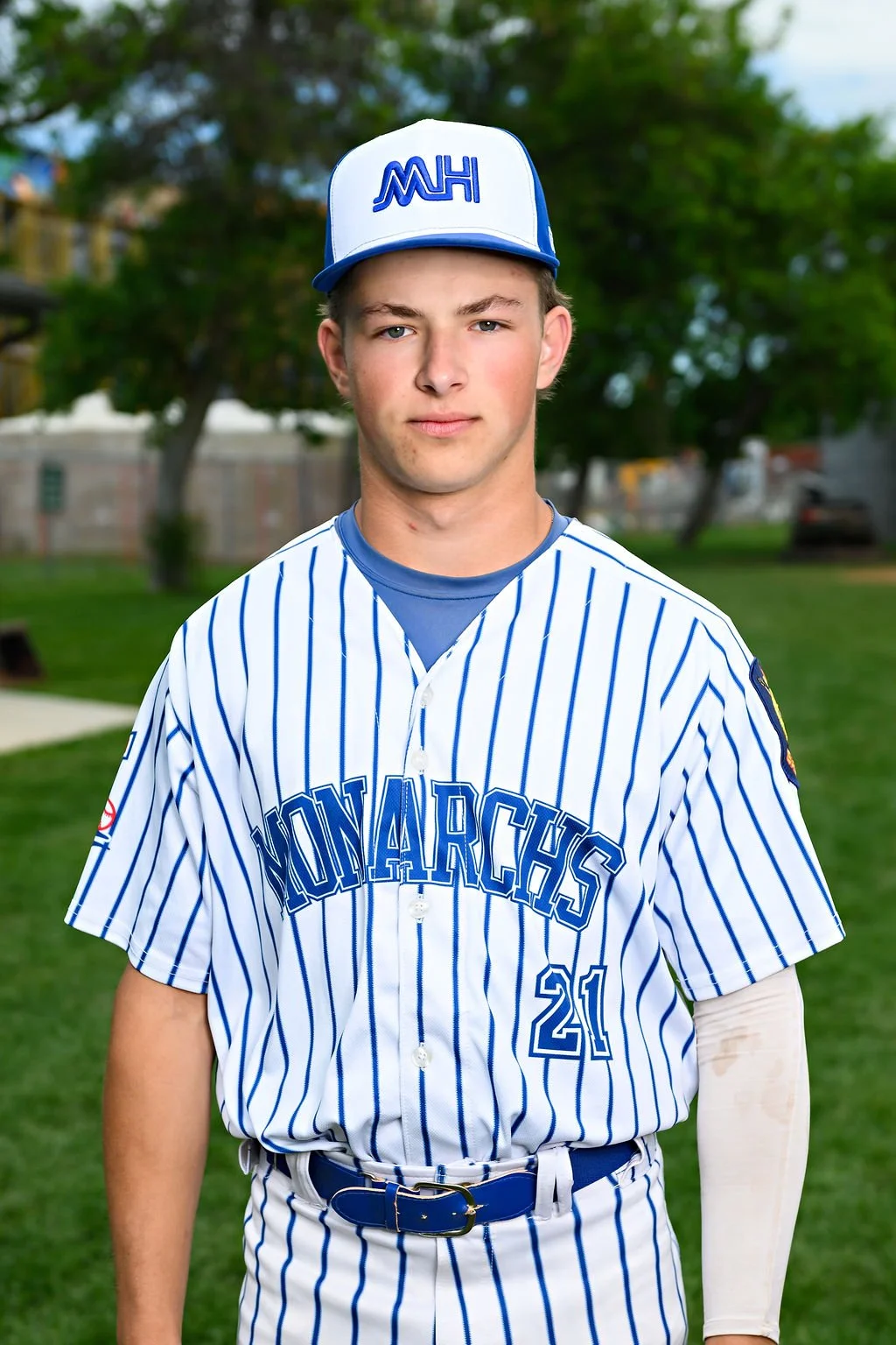 Young man in a blue baseball uniform and cap standing on a baseball field.