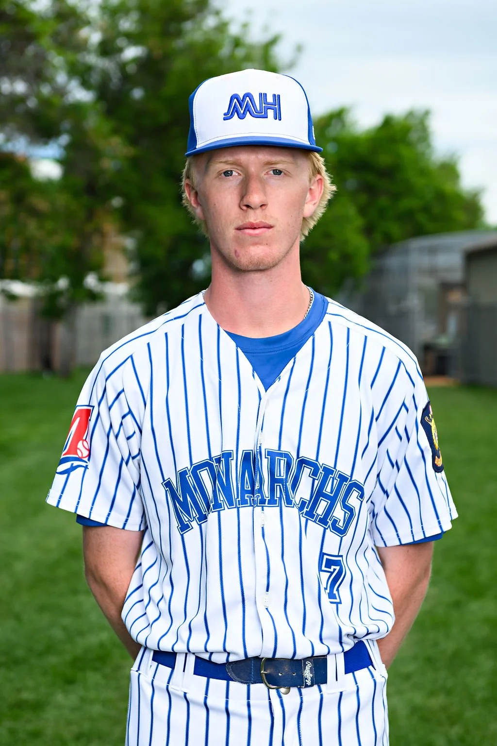 Young male baseball player wearing a blue jersey and cap, standing on a baseball field.