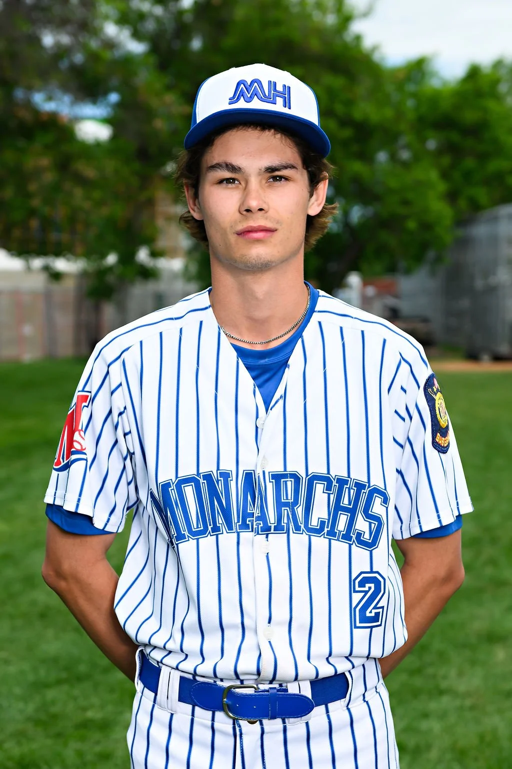 Young man in a blue baseball uniform and cap standing on a baseball field.