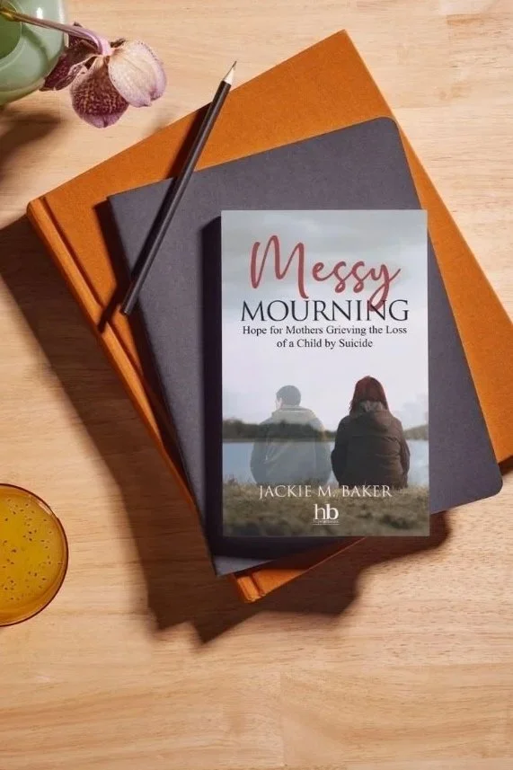 Jackie M. Baker's Book stylized on a stack of books on a table
