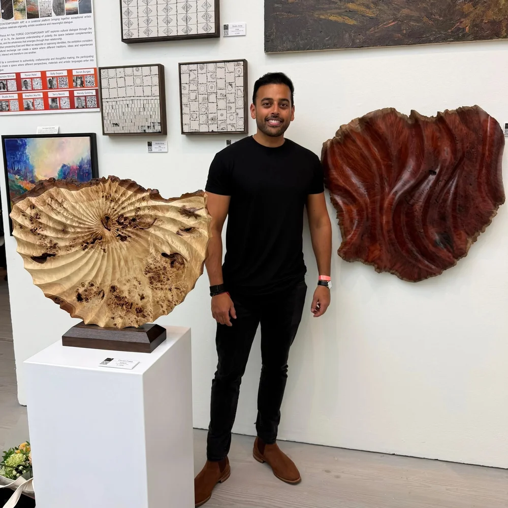 Pavan Patel standing between two of his carved burl sculptures at an exhibition