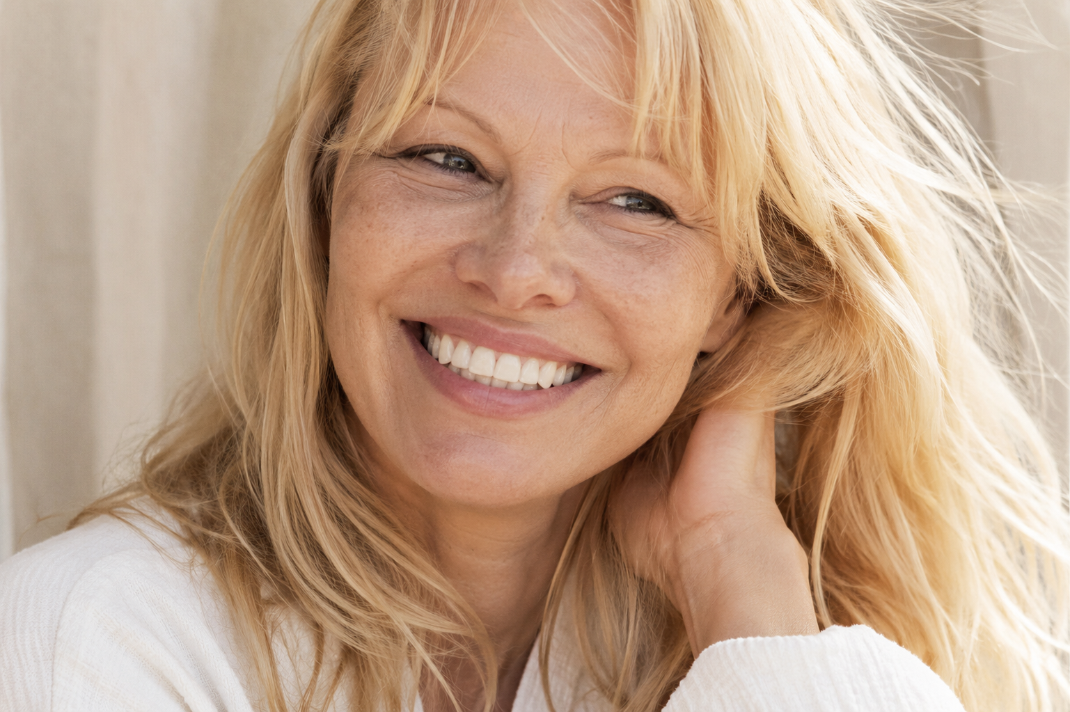 Radiant mature woman smiling with natural skin texture and expression lines, representing healthy aging and facial vitality